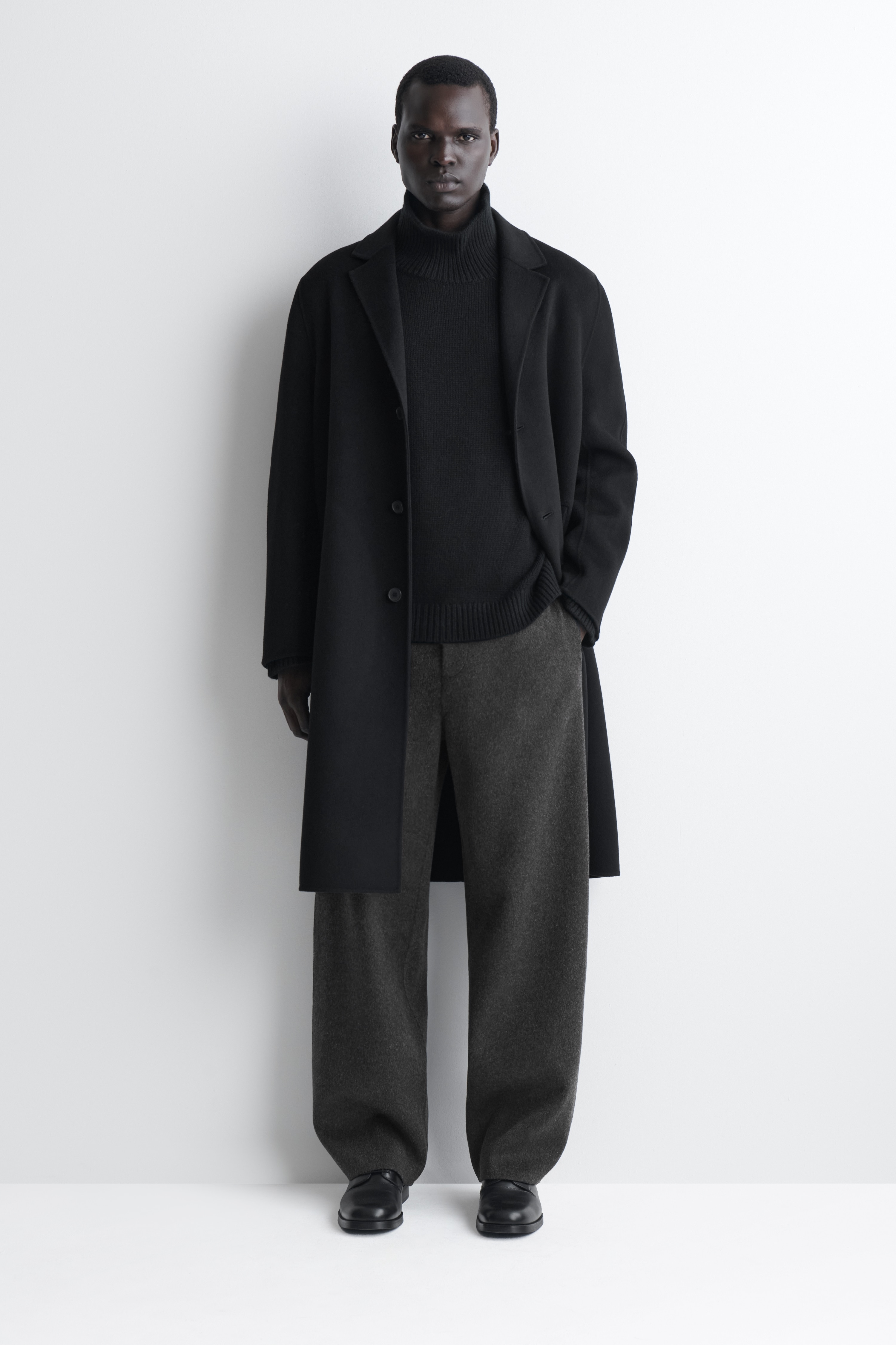 I pantaloni a gamba larga in lana double face, dalla vestibilitÃ  rilassata, sono mostrati frontalmente e presentano un tessuto in lana testurizzato di colore grigio antracite scuro. Sono progettati con una cintura strutturata dotata di passanti per cintura, patta frontale nascosta e una silhouette dritta a gamba larga.