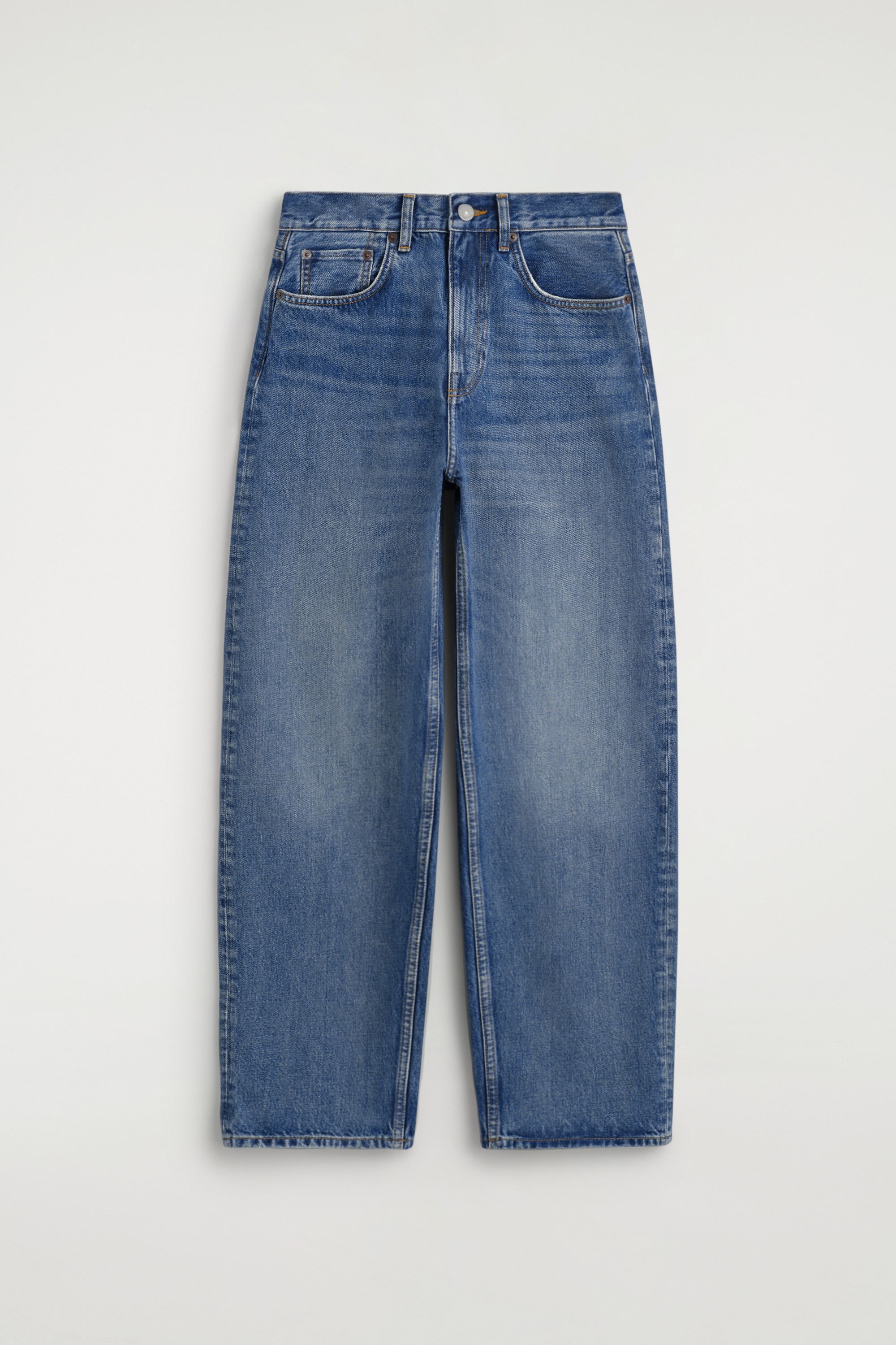 Ein Model trÃ¤gt das blau gestreifte Baumwollhemd mit umgeschlagenen Manschetten in frontaler Ansicht, wobei die hochgekrempelten Ãrmel die kontrastierenden weiÃen Manschetten eines darunter getragenen weiÃen Hemds sichtbar machen. Das gestreifte Hemd ist in die hoch geschnittene, mittelblaue Bay Barrel-Leg-Jeans gesteckt, die eine lockere, weit geschnittene Passform mit leicht zulaufendem Saum zeigt.