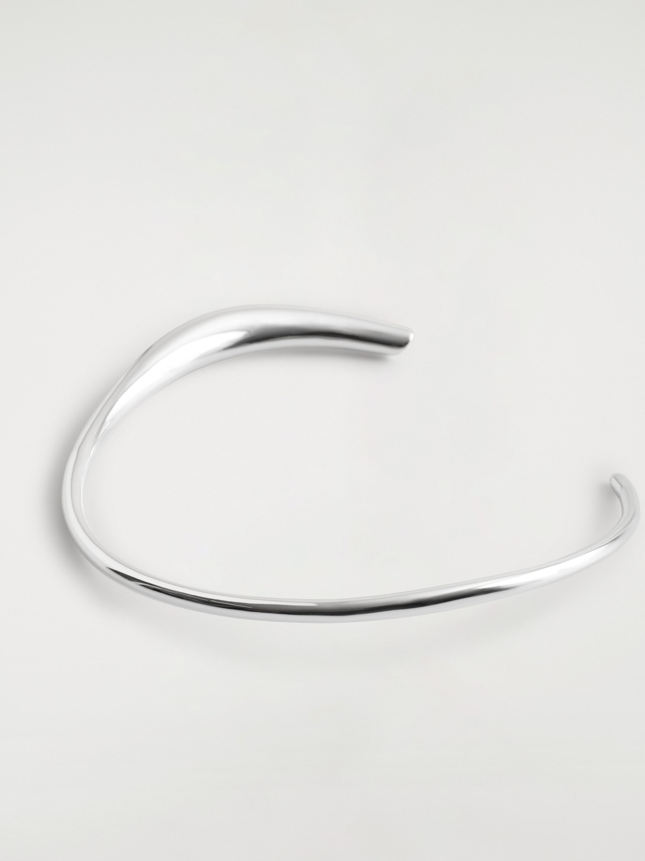 Un collier ras-du-cou en argent poli met en valeur un design torque asymétrique à extrémités ouvertes, aux courbes organiques et fluides. La pièce s’amincit d’une extrémité sculpturale épaisse et bulbeuse d’un côté à une courbe fine et délicate de l’autre. Un collier ras-du-cou en argent poli met en valeur un design torque asymétrique à extrémités ouvertes, aux courbes organiques et fluides. La pièce s’amincit d’une extrémité sculpturale épaisse et bulbeuse d’un côté à une courbe fine et délicate de l’autre.