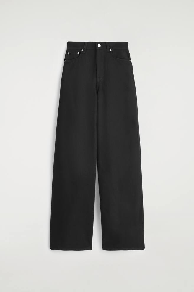 Zwarte jeans met wijde pijpen worden van voren gepresenteerd, met een hoge taille en een zilveren knoopsluiting en riemlussen. De jeans heeft de klassieke vijfzakkenstijl met zilveren klinknagels en een ontspannen, volledige lengte. - 1
