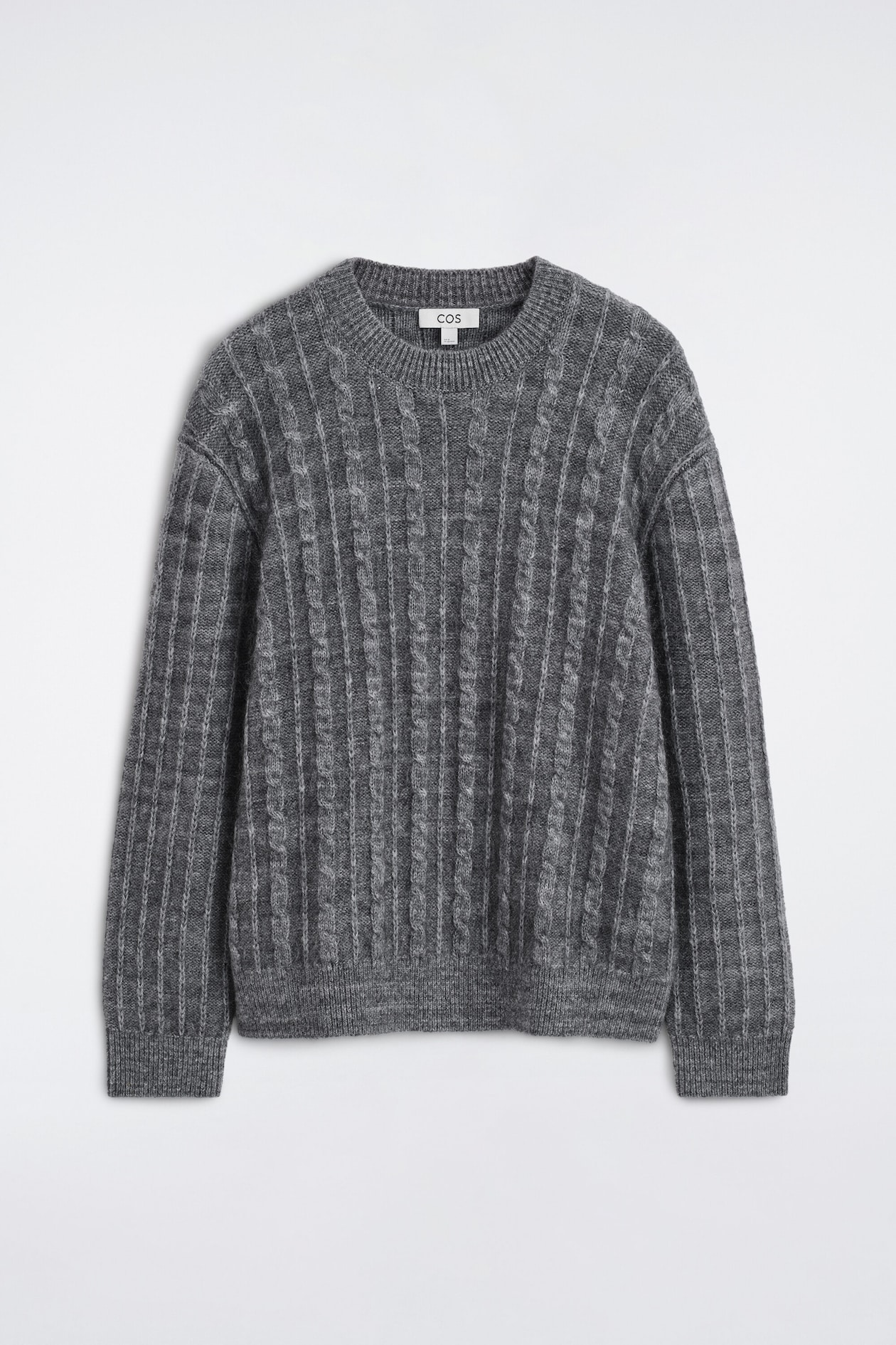 A grey cable-knit crewneck sweater is facing front, displaying vertical cable and ribbed knit patterns across the body and long sleeves. The sweater features a ribbed collar, ribbed cuffs, and a ribbed hem.