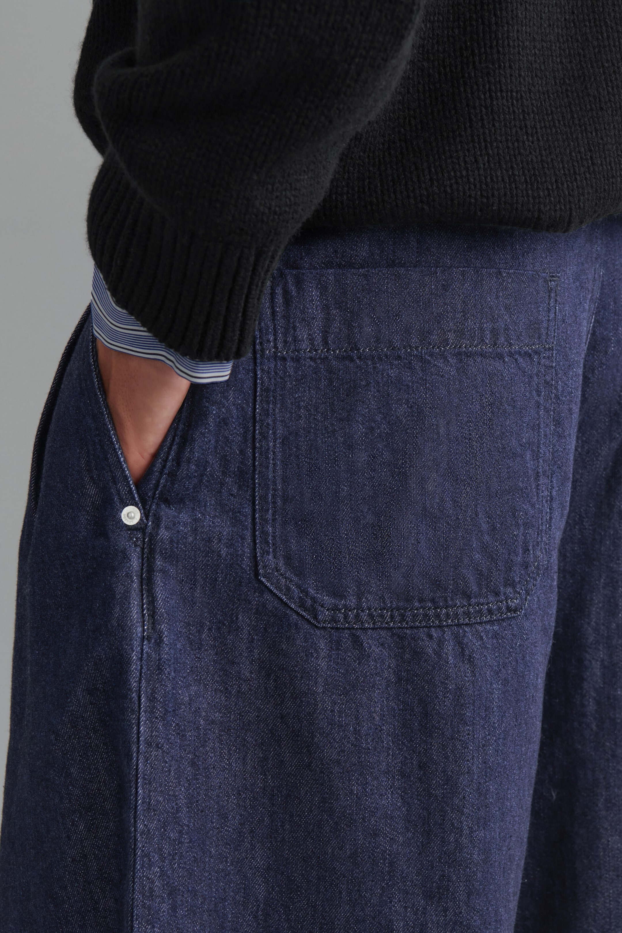 Le pantalon barrel à jambes larges en denim plissé et coupe décontractée est présenté en vue de trois quarts dos, avec une grande poche plaquée arrière et une poche latérale insérée ornée d’un petit détail rivet blanc. Un pull en maille côtelée noir et le poignet d’une chemise rayée sont superposés sur la ceinture, tandis qu’une main repose dans la poche latérale pour mettre en valeur la coupe décontractée. Le pantalon barrel à jambes larges en denim plissé et coupe décontractée est présenté en vue de trois quarts dos, avec une grande poche plaquée arrière et une poche latérale insérée ornée d’un petit détail rivet blanc. Un pull en maille côtelée noir et le poignet d’une chemise rayée sont superposés sur la ceinture, tandis qu’une main repose dans la poche latérale pour mettre en valeur la coupe décontractée.