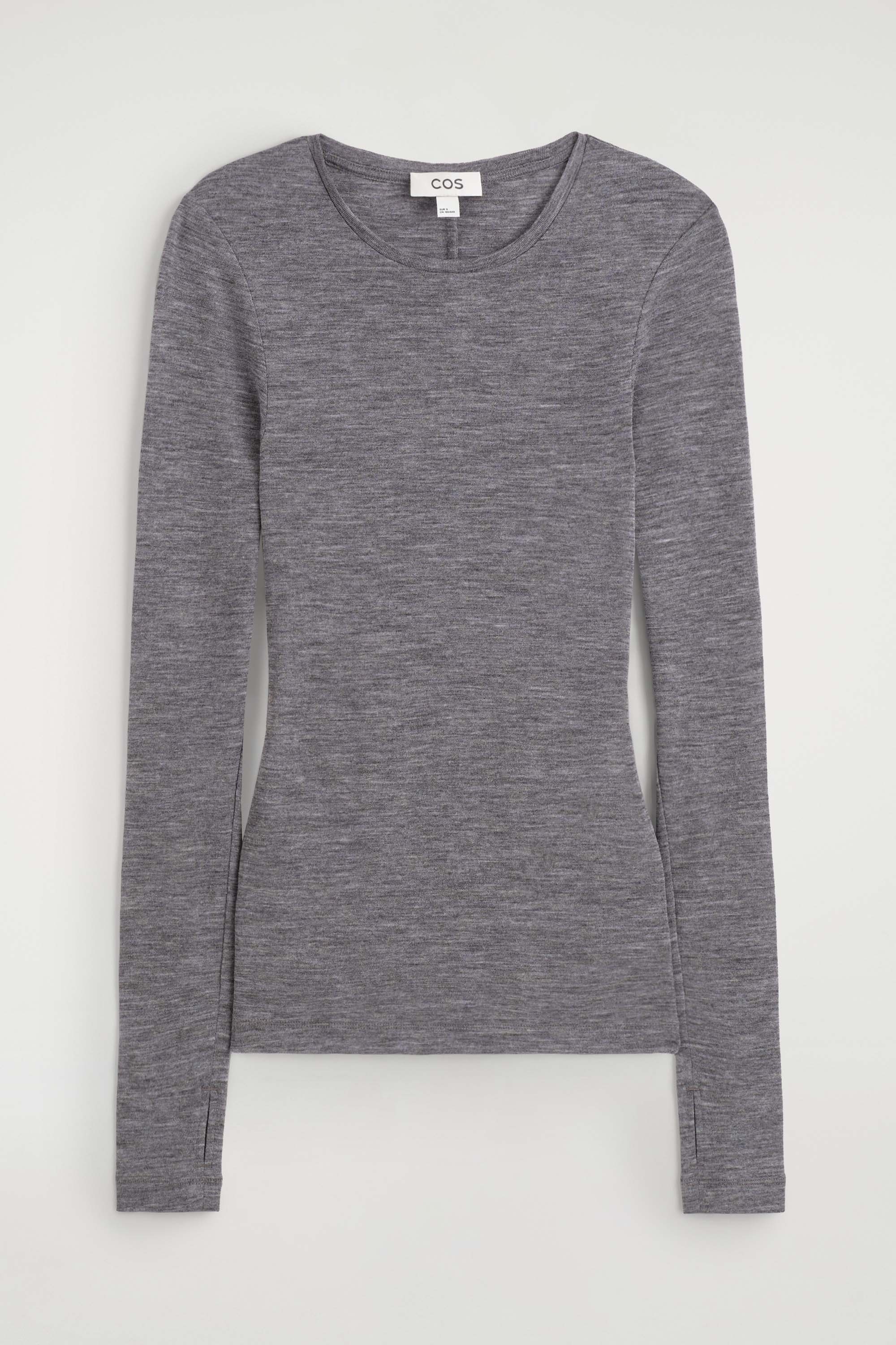Un haut en laine mÃ©rinos gris, coupe slim et Ã  col rond, est portÃ© par le mannequin comme couche de base. Le haut Ã  manches longues est stylisÃ© sous un blazer noir ouvert et rentrÃ© dans un pantalon noir Ã  jambes larges.