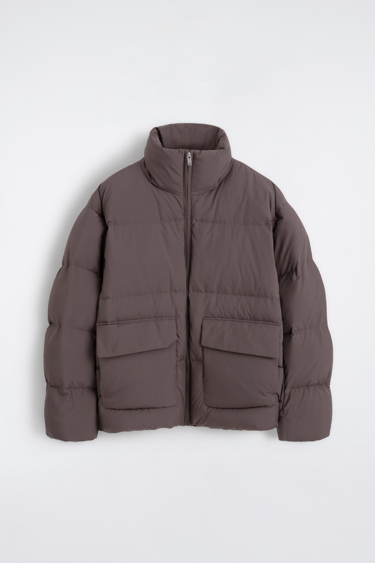 The funnel-neck nylon down puffer jacket in dark taupe is shown from the front, featuring horizontal quilting and a full-length front zipper. It has a high stand-up collar and two large rectangular flap pockets on the lower front.