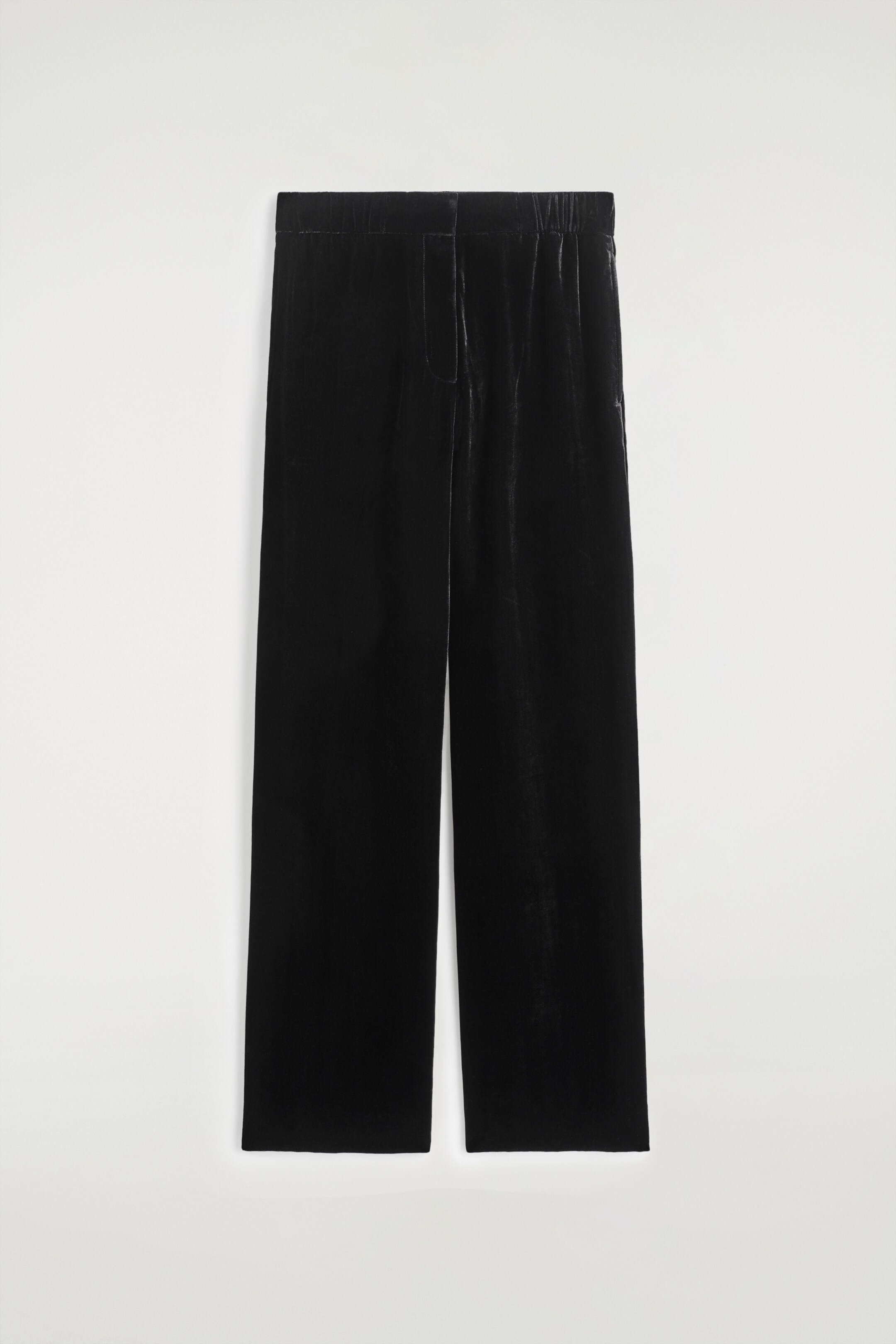 Agrandir l'image: Un pantalon large en velours noir est affiché DE FACE, avec une taille élastiquée et une fermeture à boutons apparente. Le tissu de velours doux reflète subtilement la lumière.