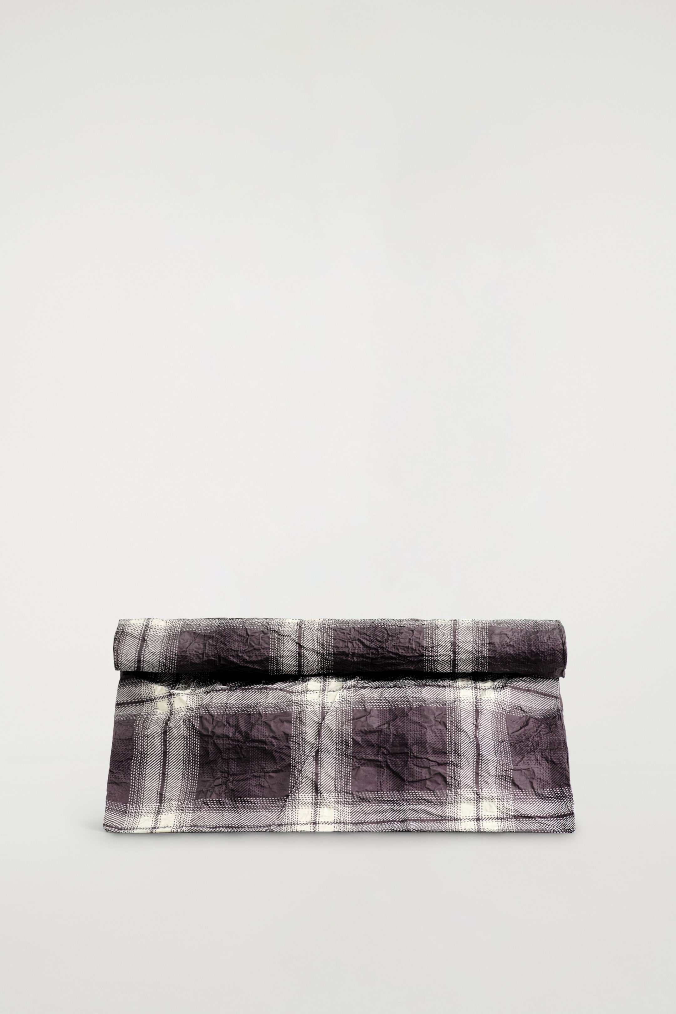 Ver imagem maior: Uma clutch bag voltada para a frente apresenta um fecho superior enrolado. É feita de tecido enrugado e exibe um padrão xadrez em tons de cinza-púrpura escuro e cinza claro.