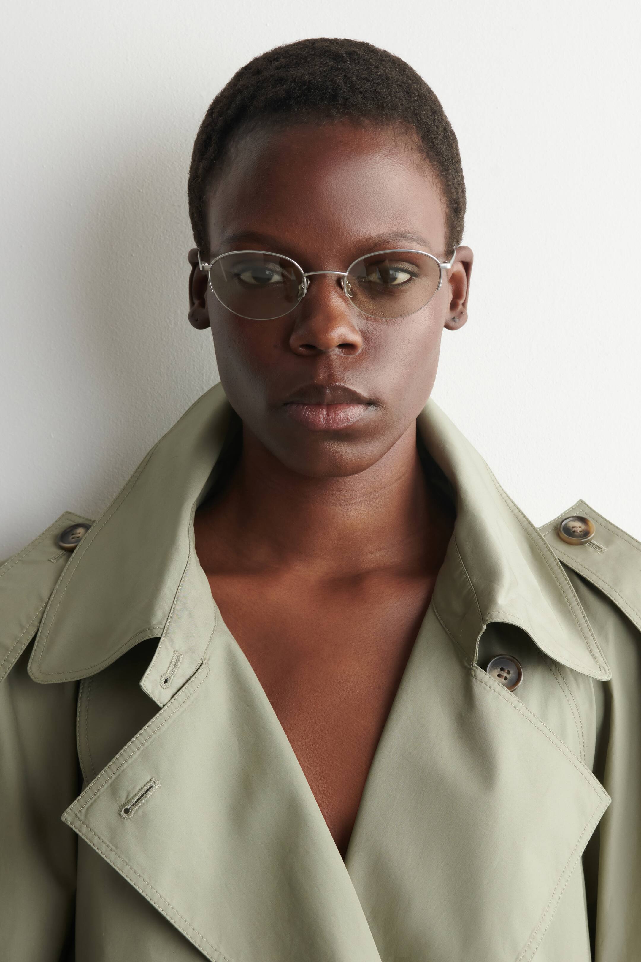 Größeres Bild anzeigen: Die Sonnenbrille verfügt über runde Rahmen, die halb mit silberfarbenem Metall eingefasst sind, und präsentiert hellbeige Gläser.