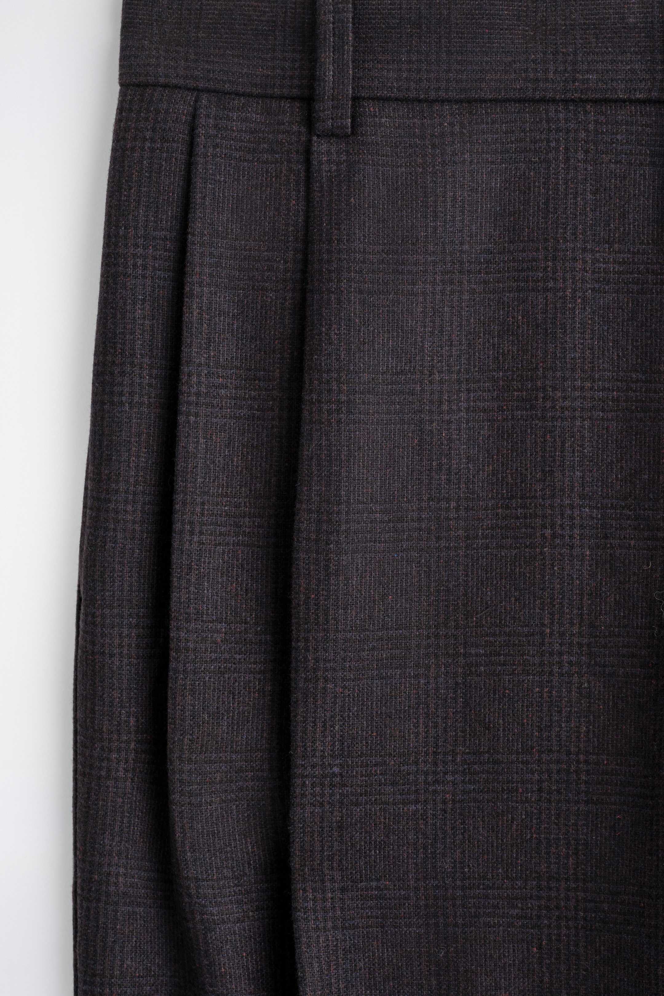 Agrandir l'image: Un pantalon noir mélangé est présenté de face, avec un motif à carreaux subtil et des détails plissés s'étendant depuis la taille.