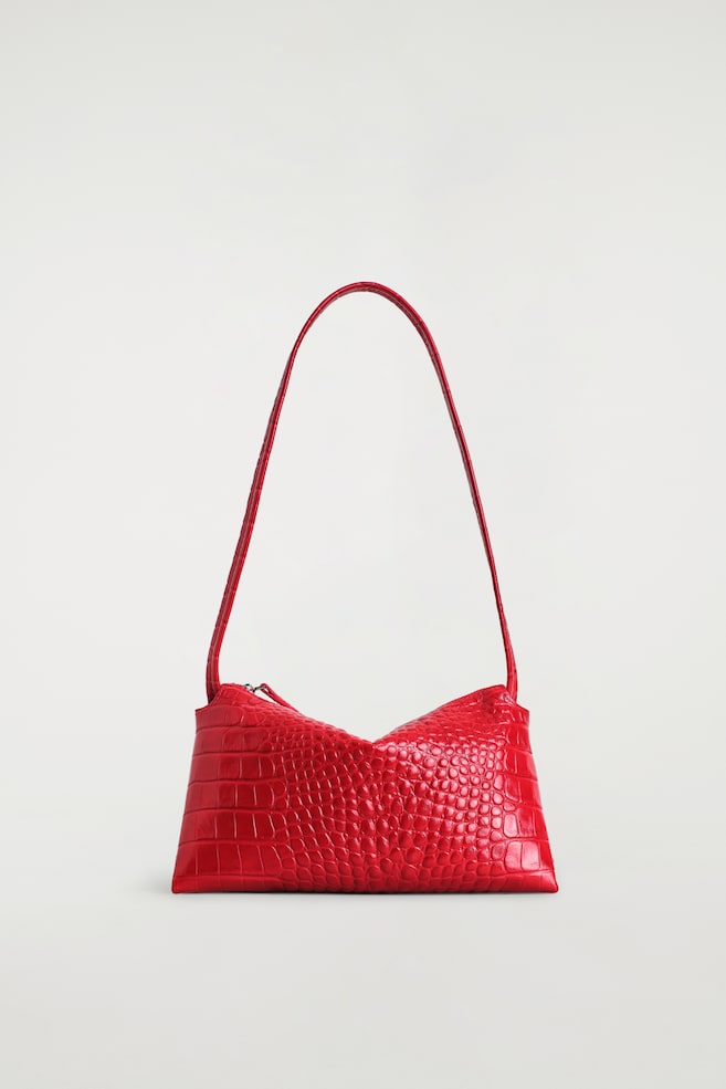 Die Mini Pavilion Shoulder Bag ist in einer Frontalansicht zu sehen und verfügt über ein leuchtend rotes, krokodilgeprägtes Leder-Finish. Sie zeigt eine strukturierte, rechteckige Silhouette mit einer markanten, abfallenden oberen Kante und einem langen, schlanken, farblich passenden Schulterriemen. - 1