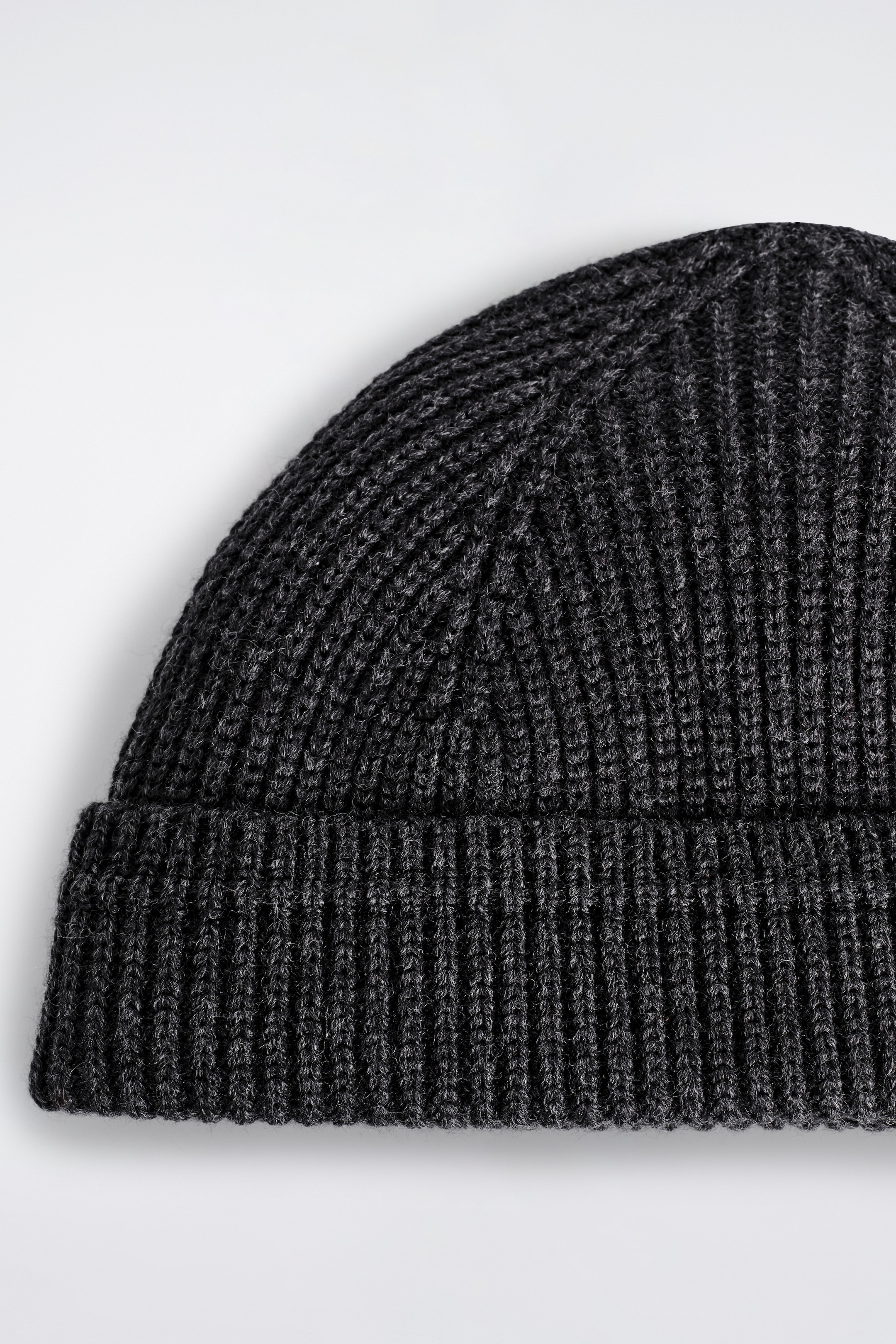 Agrandir l'image: Un bonnet gris foncé moucheté est présenté, avec un tricot côtelé épais et un bord court replié.