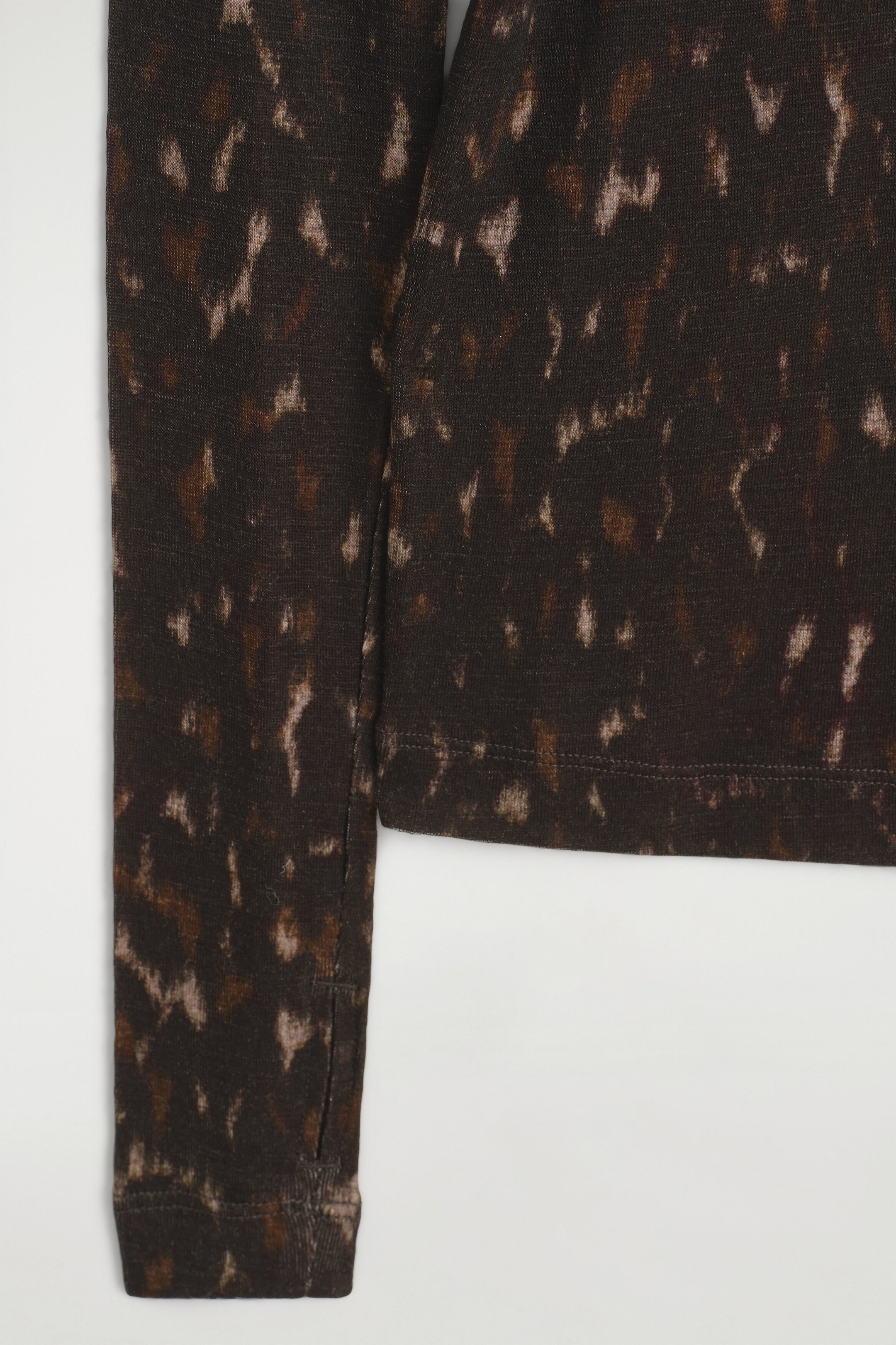 Das High-Neck-Top aus Merinowolle präsentiert sich in einem dunkelbraunen Strickstoff mit abstraktem, gesprenkeltem Muster in Beige und Hellbraun. Diese Nahaufnahme hebt den langen Ärmel mit einem dezenten Schlitzdetail am Bündchen sowie die saubere, gestickte Saumlinie des Körpers hervor. Das High-Neck-Top aus Merinowolle präsentiert sich in einem dunkelbraunen Strickstoff mit abstraktem, gesprenkeltem Muster in Beige und Hellbraun. Diese Nahaufnahme hebt den langen Ärmel mit einem dezenten Schlitzdetail am Bündchen sowie die saubere, gestickte Saumlinie des Körpers hervor.