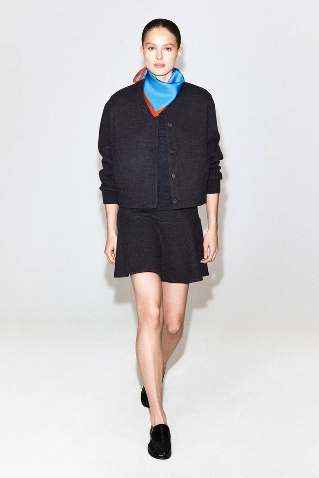 A dark grey boiled wool-blend mini skirt is being worn by the model, featuring a slightly flared silhouette. The skirt is styled as a matching set with a button-front jacket of the same material. - 1