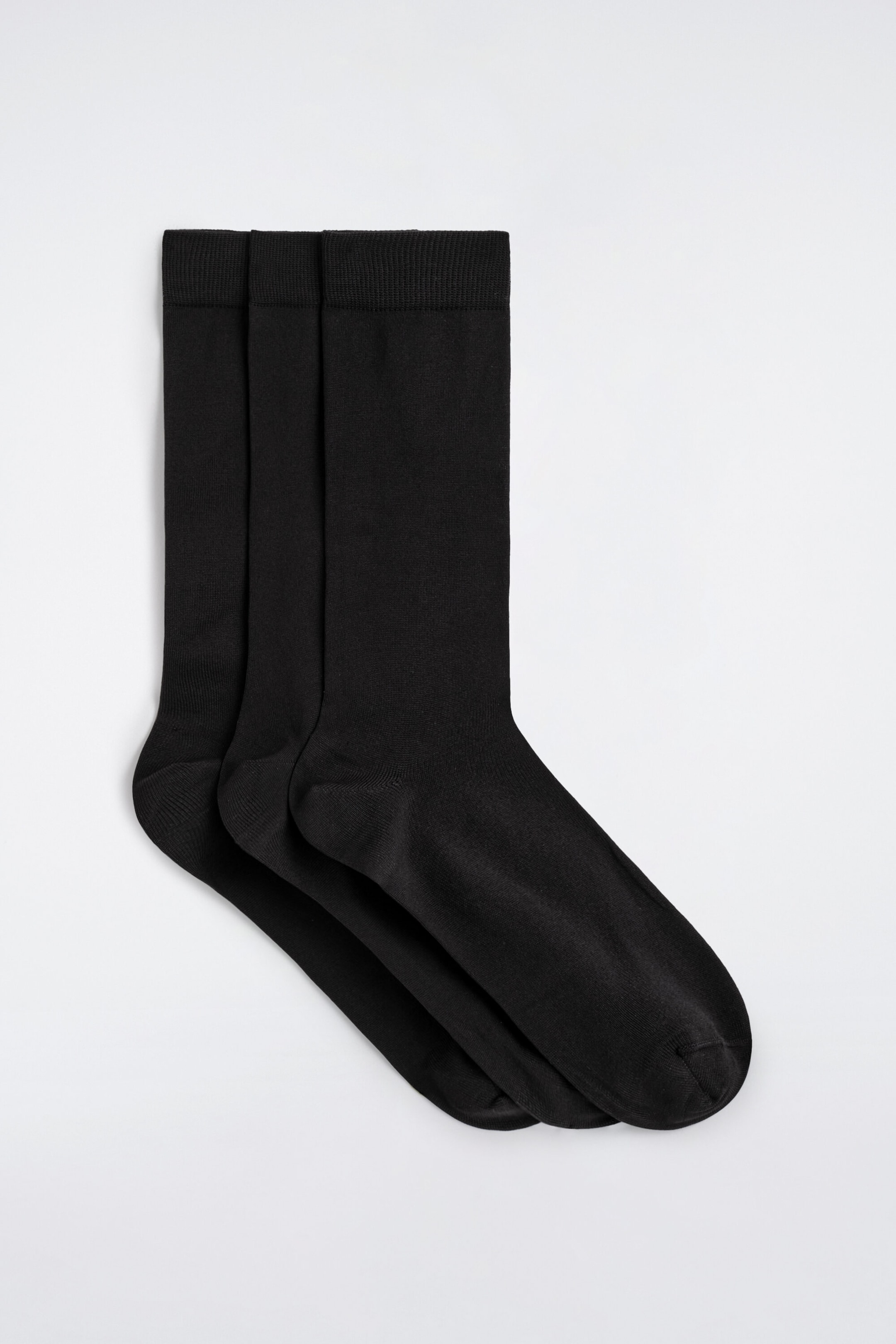 Ein Dreierpack mercerisierter Baumwollsocken zeigt drei einfarbig schwarze, fein gestrickte Crew-Socken, die diagonal übereinander angeordnet sind, um jedes Paar zu präsentieren. Die Socken verfügen über fein gerippte Bündchen, glatte Schaftpartien sowie deutlich ausgearbeitete Fersen- und Zehenbereiche.