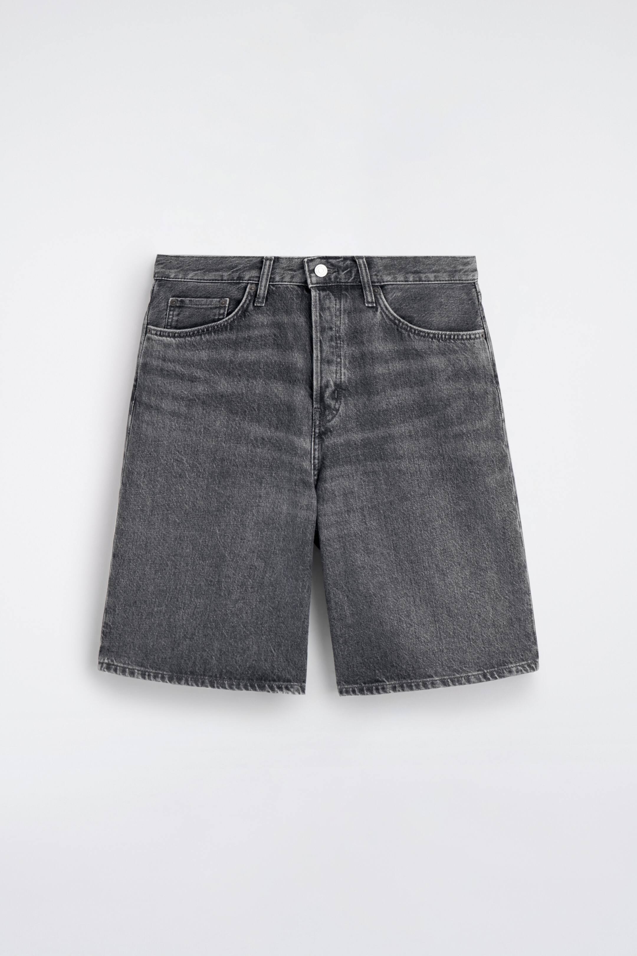 Ver imagen más grande: Pantalones cortos de mezclilla gris oscuro lavado, vistos de frente, con cierre de botón, trabillas para cinturón y dos bolsillos delanteros curvados con un pequeño bolsillo para monedas. Los pantalones cortos presentan un corte de pierna ancha, terminando por encima de la rodilla.