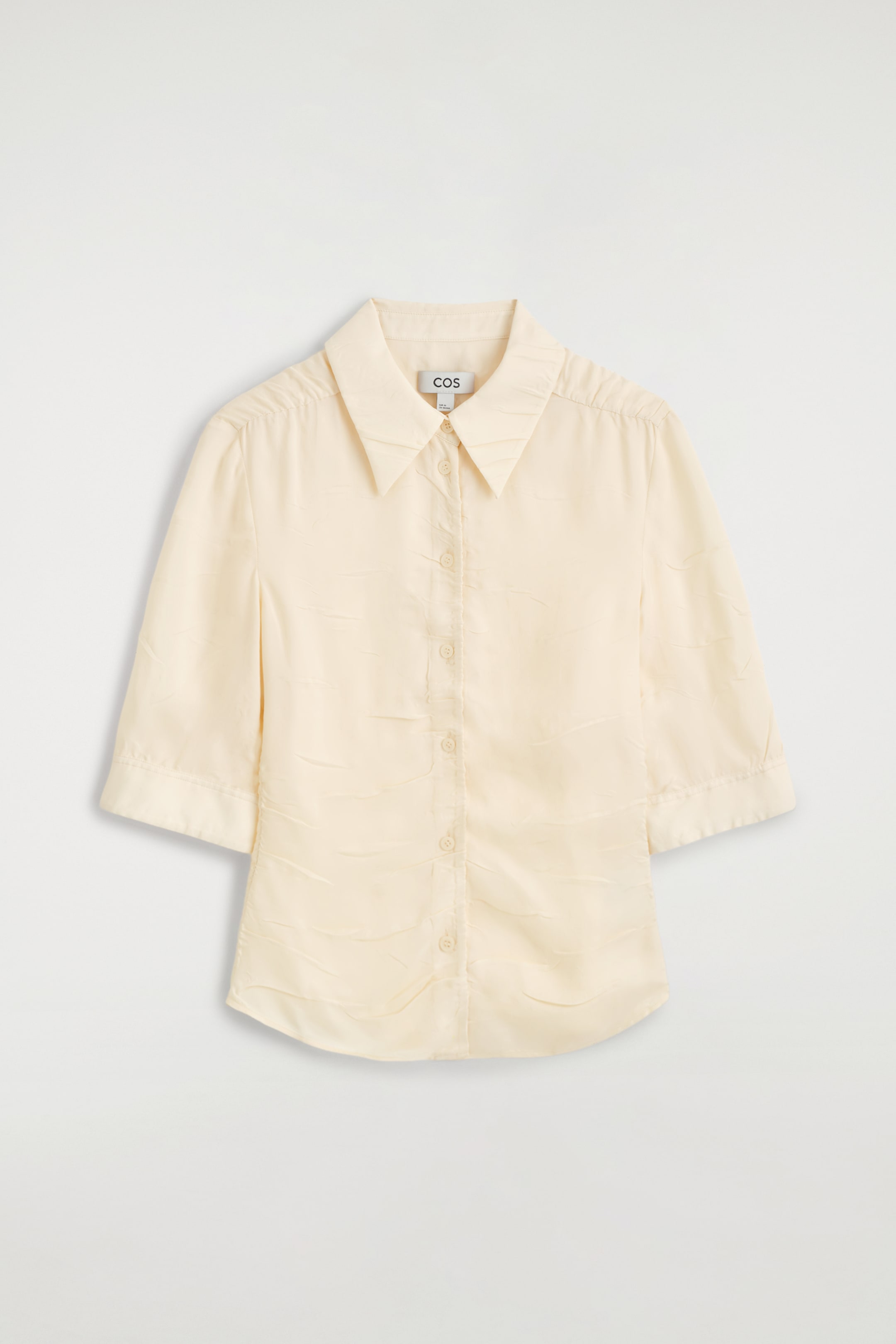 Visualizza l'immagine ingrandita: Una camicia giallo chiaro a maniche corte è mostrata frontalmente, caratterizzata da un tessuto testurizzato con effetto stropicciato e dettagli arricciati lungo l’abbottonatura e le spalle. Il design include un colletto a punta, una chiusura con bottoni e maniche lunghe fino al gomito con polsini ampi.
