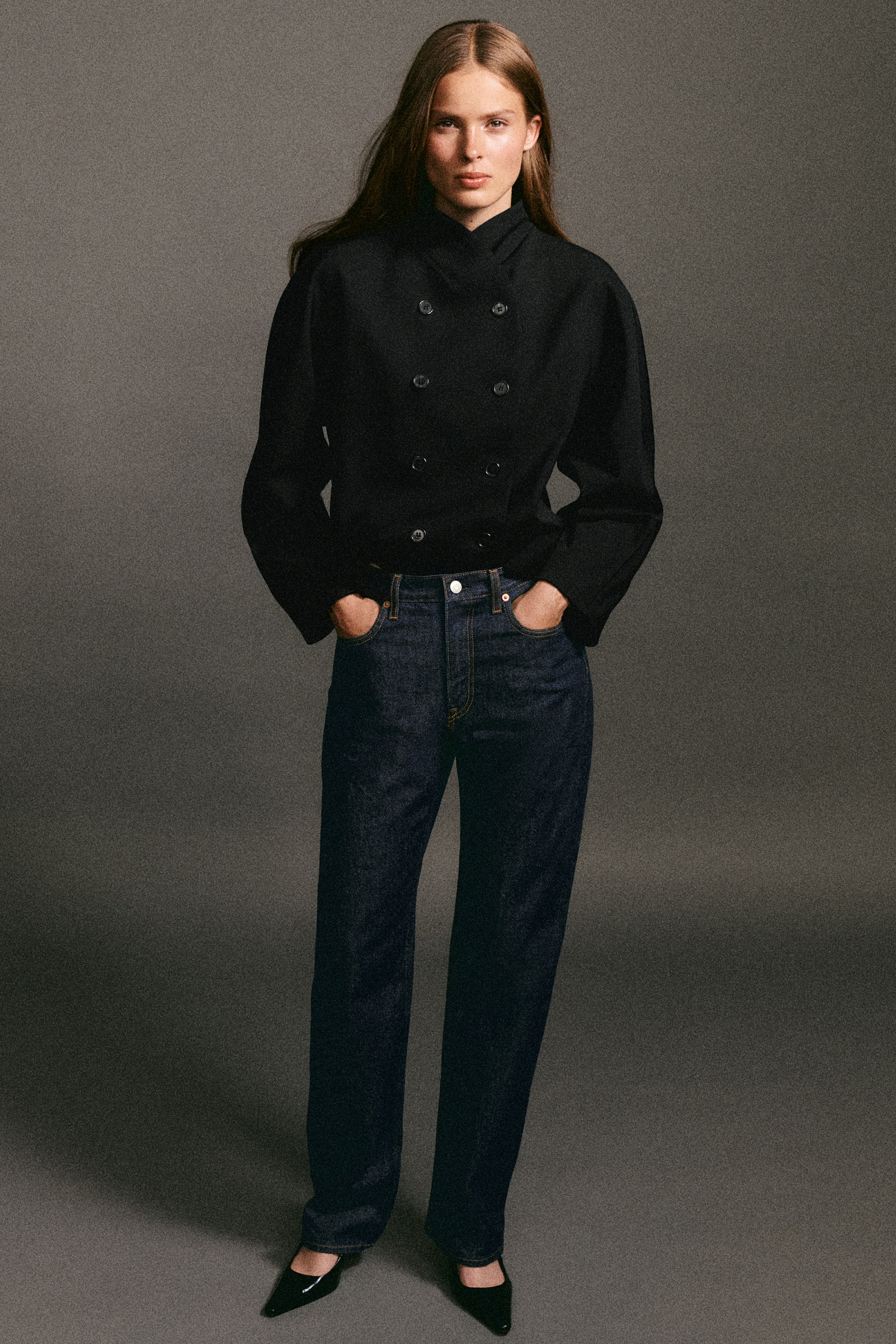 Größeres Bild ansehen: Die von vorn gezeigte schwarze Sculpted Stand-Collar Jacket präsentiert einen zweireihigen Frontknopfverschluss, strukturierte Ärmel und einen hohen Stehkragen. Sie wird mit der dunkelblauen Chord Straight-Leg Jeans kombiniert, die eine hohe Taille und eine klassische gerade Silhouette zeigt.