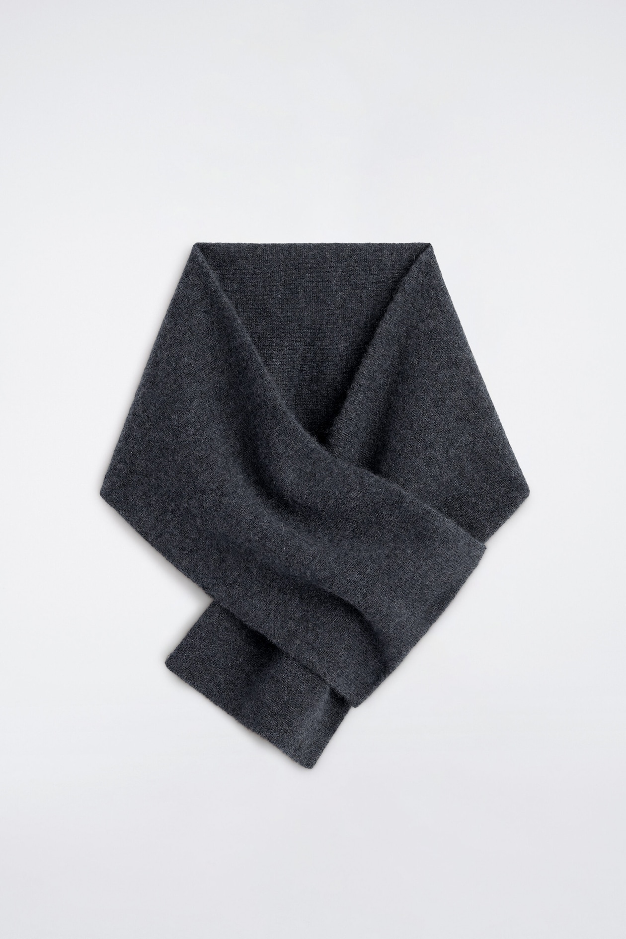 A dark gray cashmere pull-through scarf is laid flat in a front view, showcasing its soft, fine-knit texture and looped design. The scarf crosses over itself, with one end slipping through an integrated slot to create a secure, structured shape.