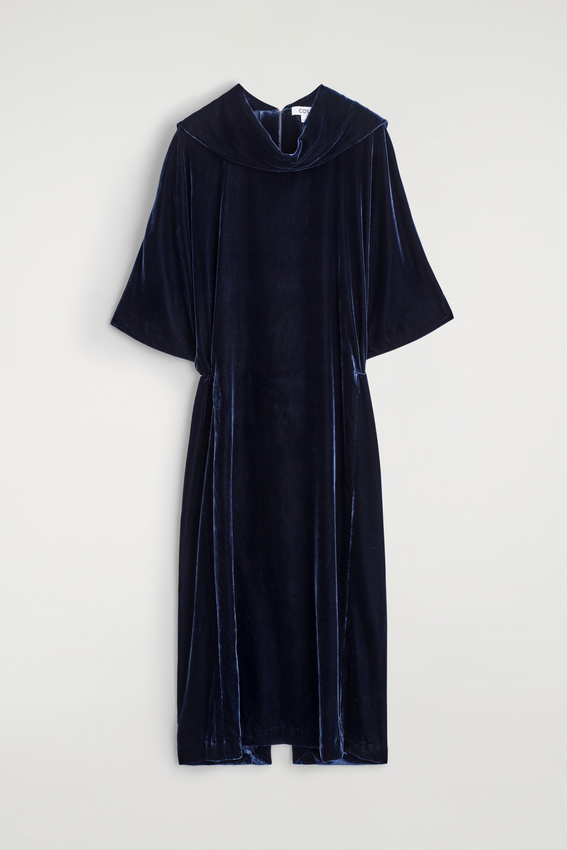 Ver imagem maior: Um vestido midi de veludo azul escuro é exibido de FRENTE, apresentando uma gola alta drapeada, mangas morcego e uma cintura blouson elástica, oferecendo um ajuste regular e comprimento midi.