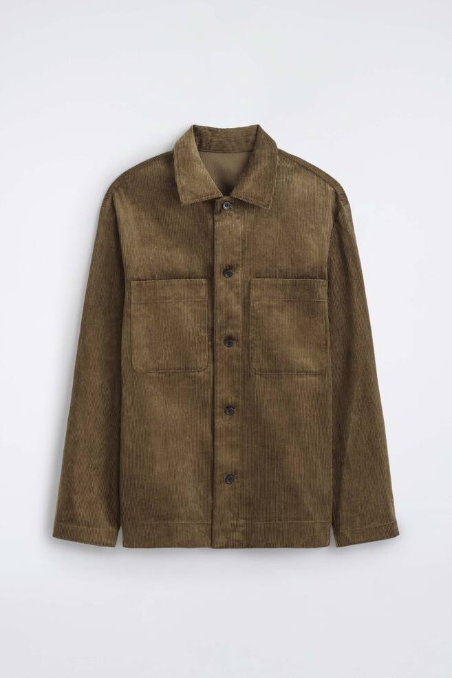 Das Overshirt aus Baumwollcord ist frontal dargestellt und verfÃ¼gt Ã¼ber einen strukturierten, olivbraunen Rippenstoff, einen klassischen Spitzkragen und einen durchgehenden Knopfverschluss vorn. Es ist mit zwei groÃen, quadratischen aufgesetzten Brusttaschen sowie langen, gerade geschnittenen Ãrmeln gestaltet. - 1