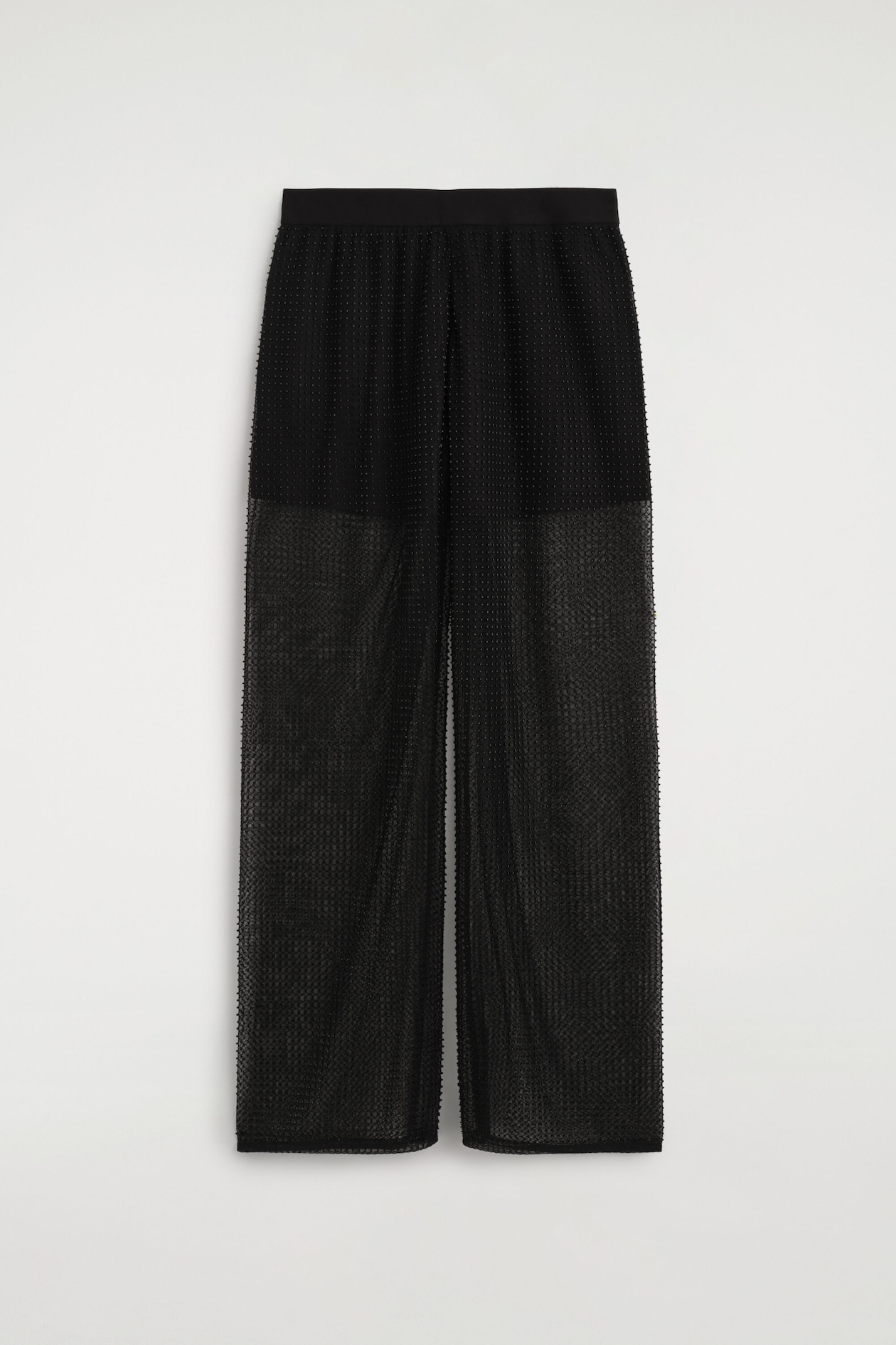 These black beaded knitted trousers are hanging straight and facing front, showcasing a wide-leg silhouette with a solid, flat waistband. The trousers are displaying a sheer, open-knit fabric embellished with tiny tonal beads, with a denser, more opaque knit section at the top.