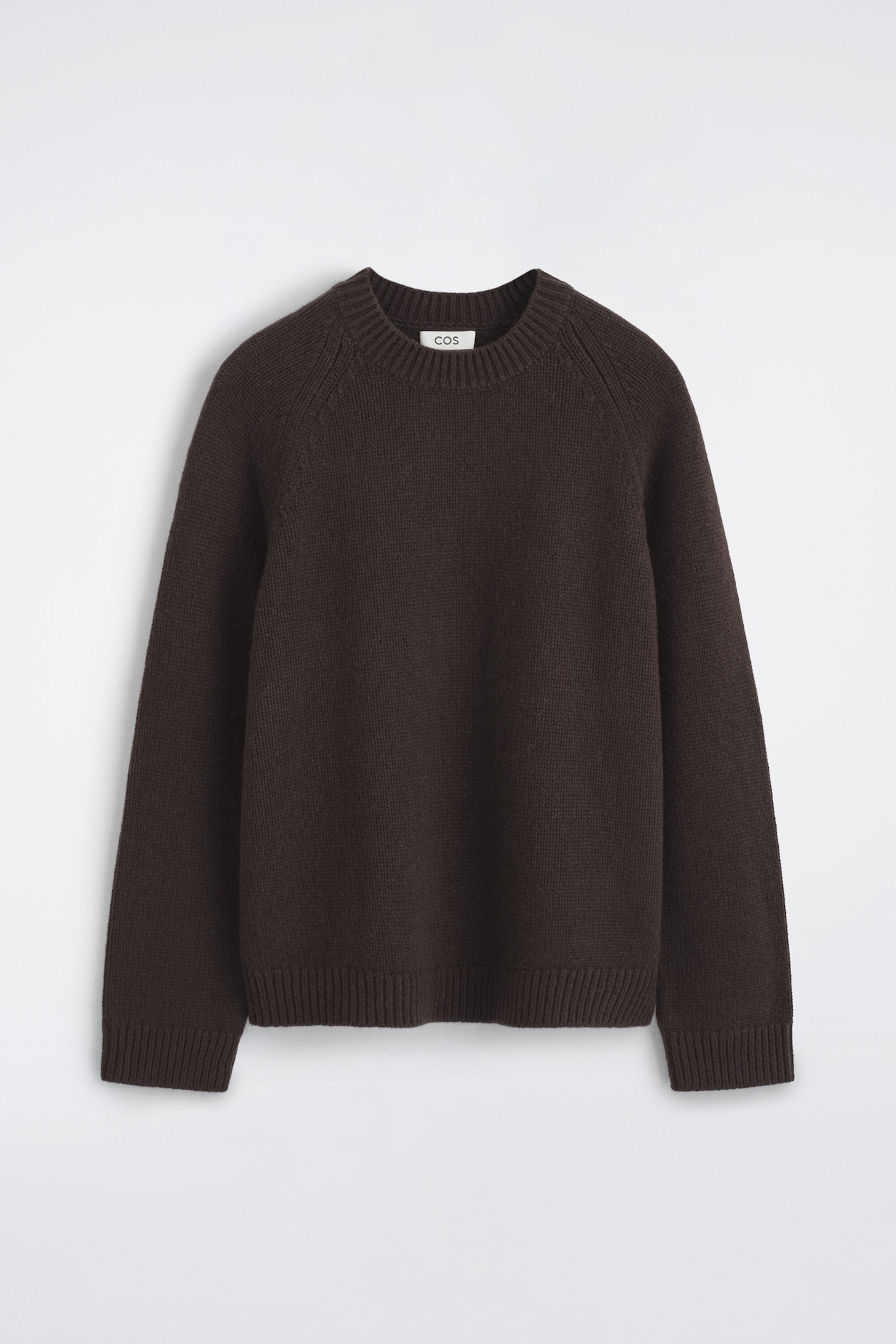 Chunky cashmere sweater in dark brown is shown from the front, featuring a ribbed crew neck, raglan sleeves, and ribbed detailing on the cuffs and hem.