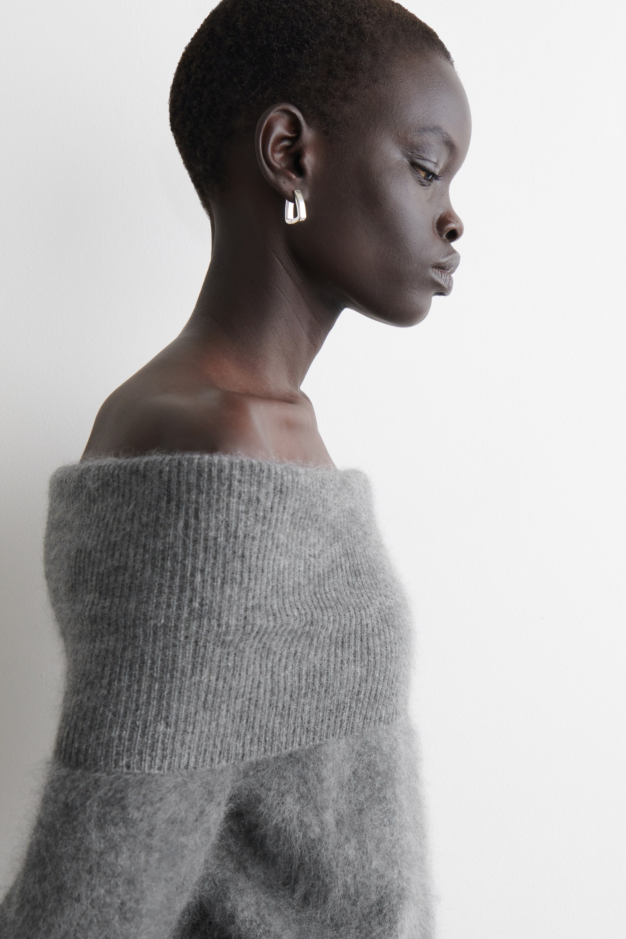 Ingrandisci l'immagine: Un TOP in lana merino grigio presenta uno scollo bardot che si piega sulle spalle, mettendo in mostra una texture spazzolata e morbida.