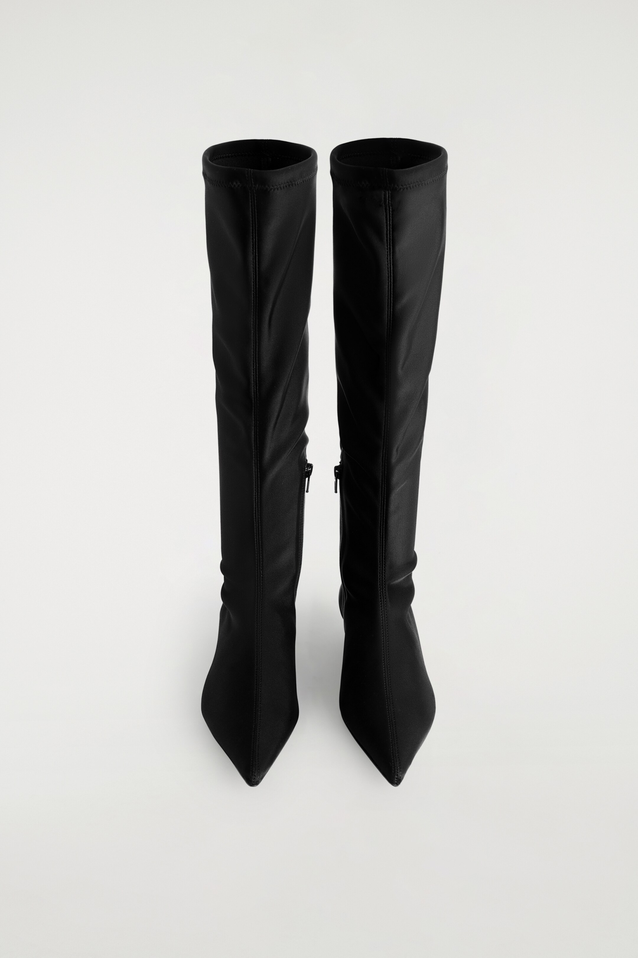 Größeres Bild ansehen: Schwarze, spitze Taucher-Kniestrumpf-Stiefel werden aufrecht präsentiert und zeigen ihr eng anliegendes Design. Jeder Stiefel verfügt über eine spitze Zehenpartie, einen glatten, flexiblen Schaft, der bis zum Knie reicht, und einen Reißverschluss, der entlang der Innenseite verläuft.