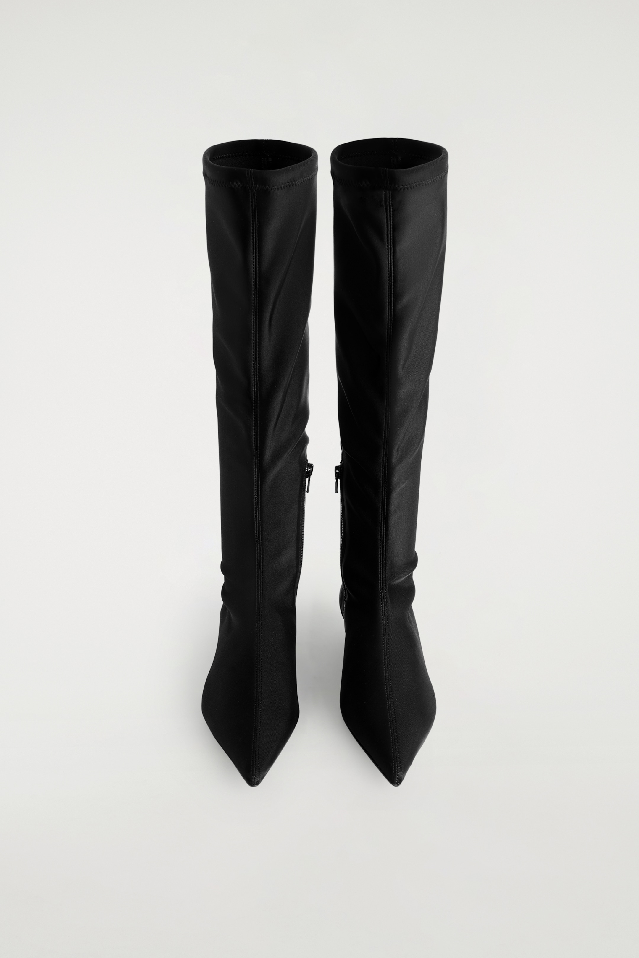 View larger image: Black pointed scuba knee sock boots are presented standing upright, showcasing their form-fitting design. Each boot is featuring a pointed toe, a smooth, flexible shaft extending to the knee, and a zipper running along the inner side.