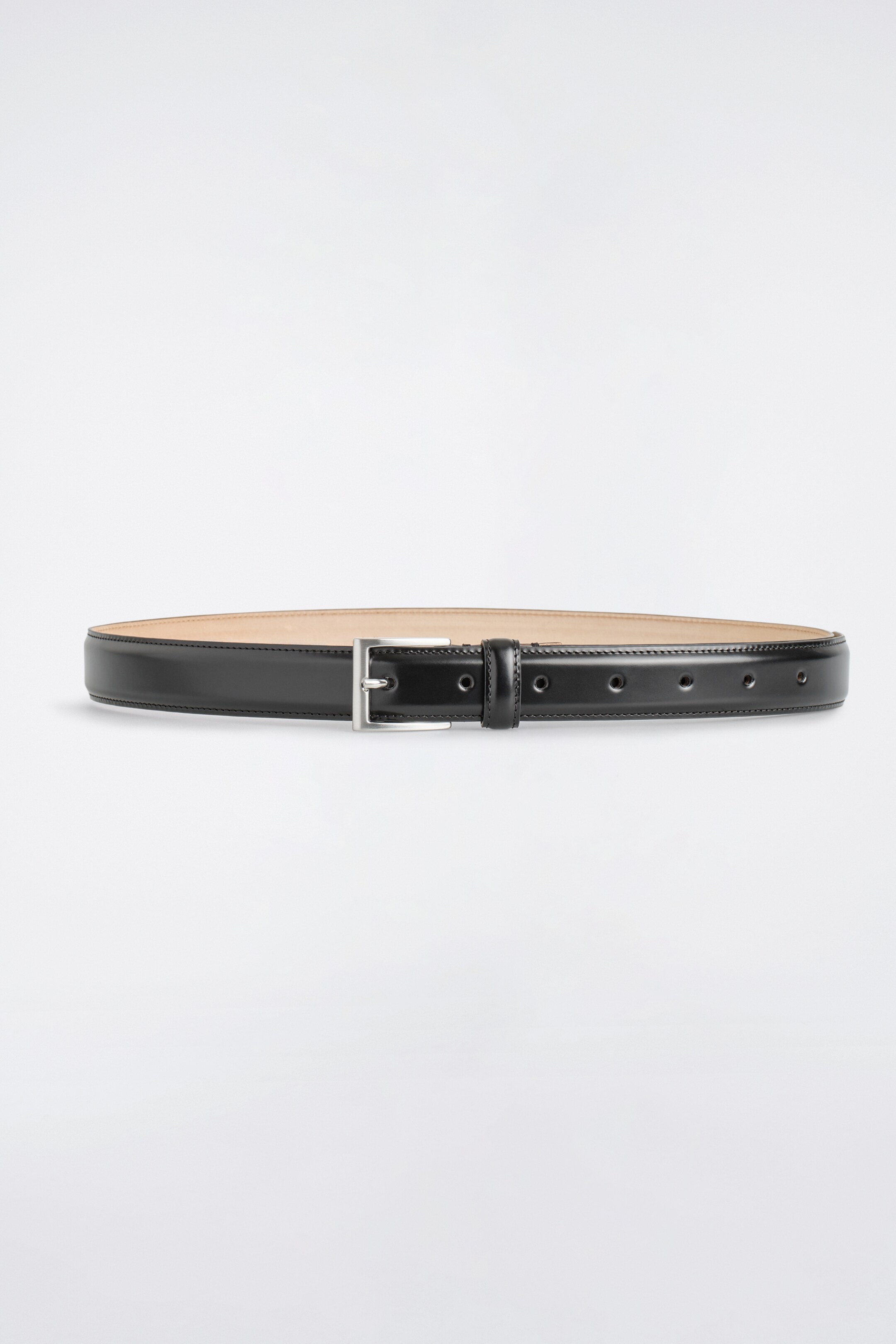 Agrandir l'image: Une ceinture en cuir noir se présente à l'AVANT, avec une boucle rectangulaire en métal argenté brossé. La ceinture présente plusieurs trous d'ajustement et un passant en cuir assorti, avec des coutures visibles sur les bords.