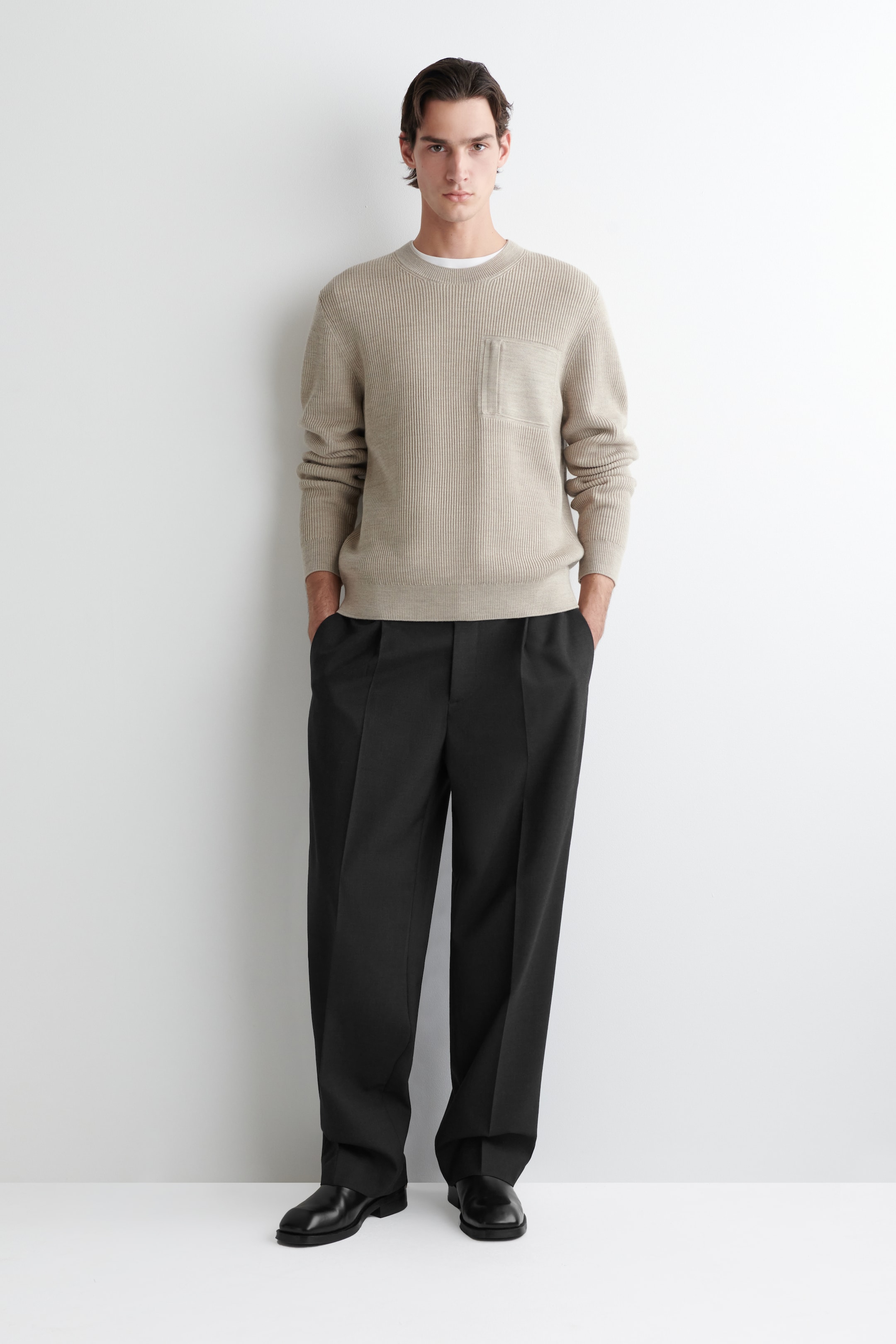 Grotere afbeelding bekijken: De POCKET-DETAIL WOOL CREW-NECK JUMPER wordt aan de VOORKANT getoond, met een licht beige geribde breisel. Het toont een ronde hals met een witte t-shirt zichtbaar eronder, een rechthoekige borstzak op de linkerborst, geribde boorden en een geribde zoom.