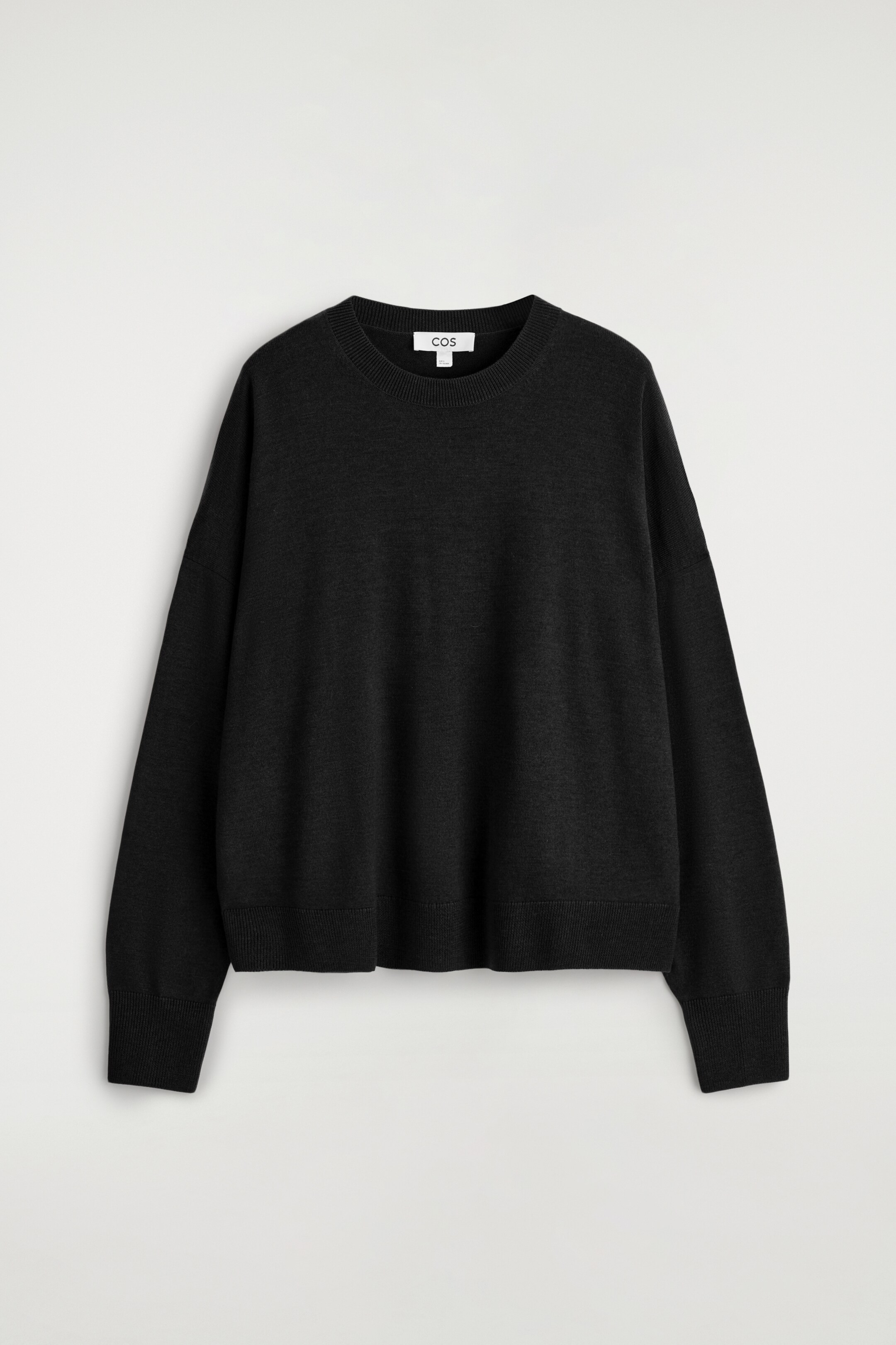 Agrandir l'image: Un pull noir à coupe décontractée est présenté de face, avec une texture finement tricotée, un col rond côtelé, des épaules tombantes, et des poignets et un ourlet côtelés.