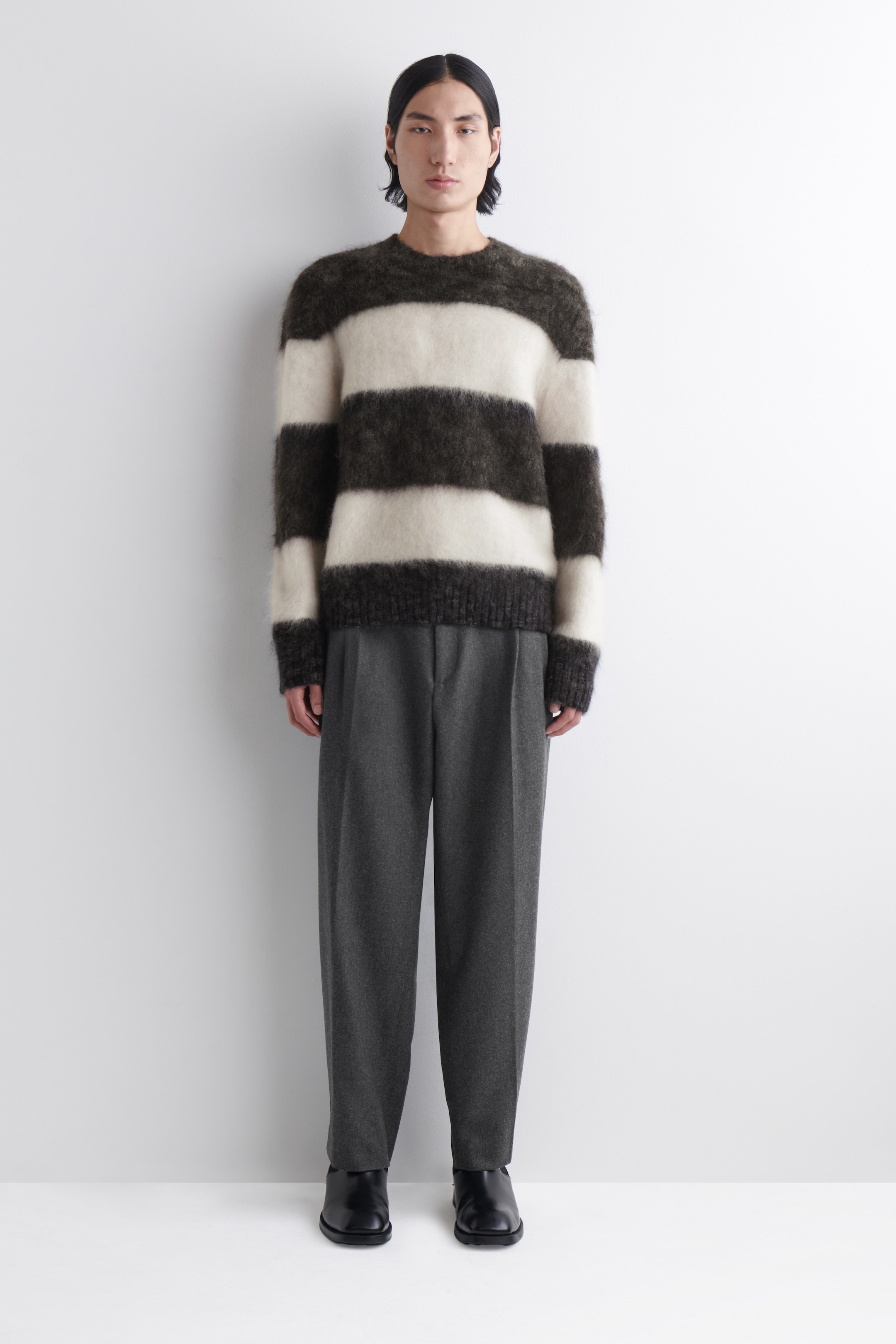 Agrandir l'image: Un pull ras-du-cou duveteux présente de larges rayures horizontales en gris foncé et blanc cassé, avec une coupe décontractée. Des poignets et un ourlet côtelés complètent son design.