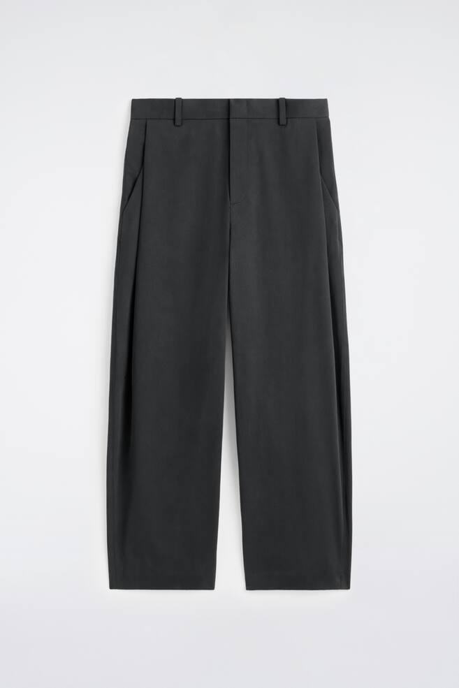 FRONT of dark grey wide-leg trousers, showcasing a relaxed cut. The trousers feature a flat waistband with belt loops, precise front pleats, and slanted side pockets. - 1