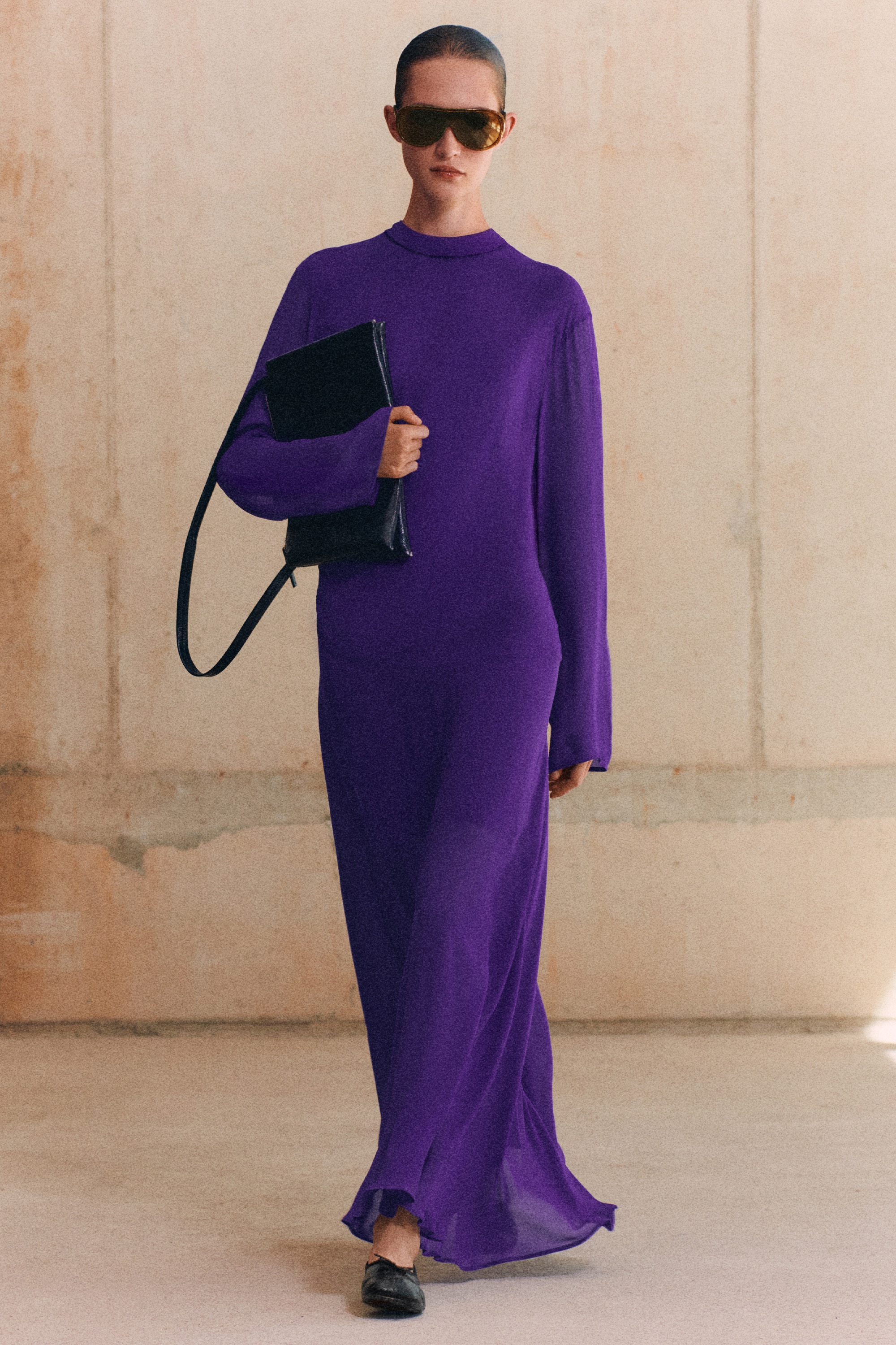 Um vestido roxo de manga comprida estÃ¡ virado para a frente, com gola alta tipo mock neck e mangas compridas e largas. O design destaca um franzido drapeado assimÃ©trico num dos lados da cintura, criando pregas suaves ao longo do corpete antes de descer para uma saia midi de corte descontraÃ­do.