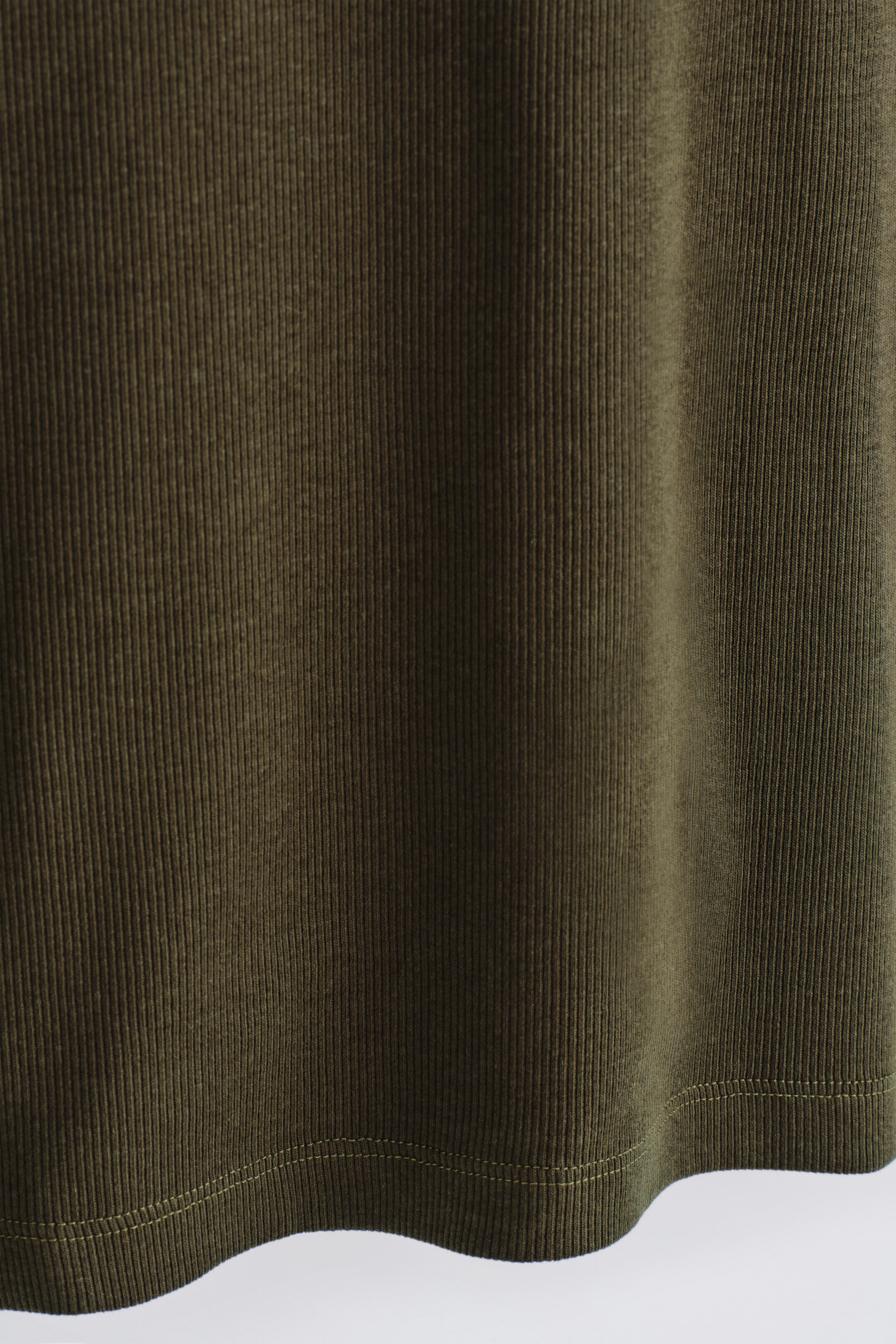 Visualizza immagine più grande: Il prodotto è un tessuto verde oliva scuro, che presenta una sottile texture a coste e un orlo cucito visibile lungo il bordo inferiore.
