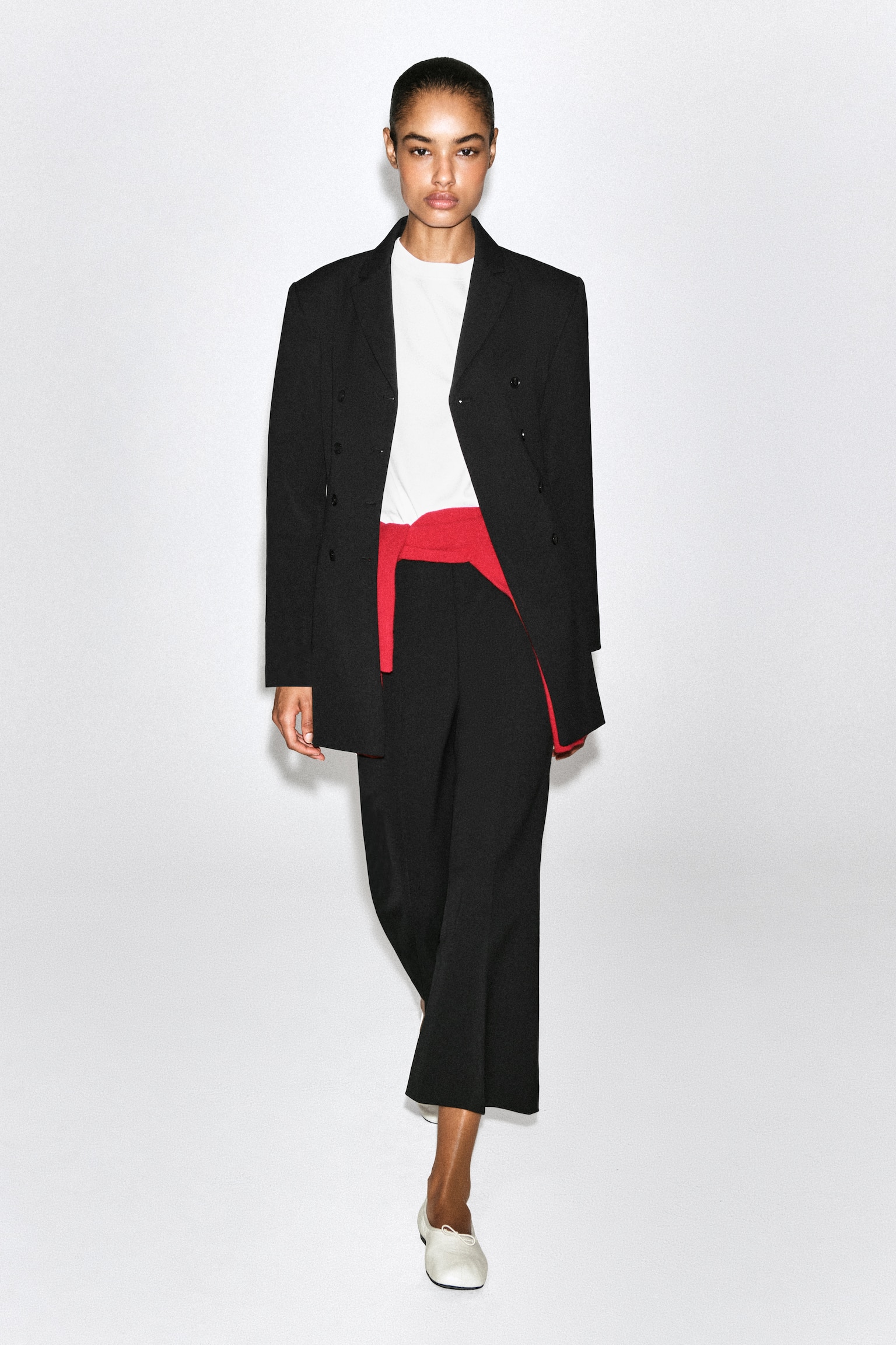 These black cropped flared trousers are shown from the front, featuring a clean, high-waisted design. Sharp pressed creases run down the centre of each leg, which widens towards the hem to create a structured, flared silhouette. - 1