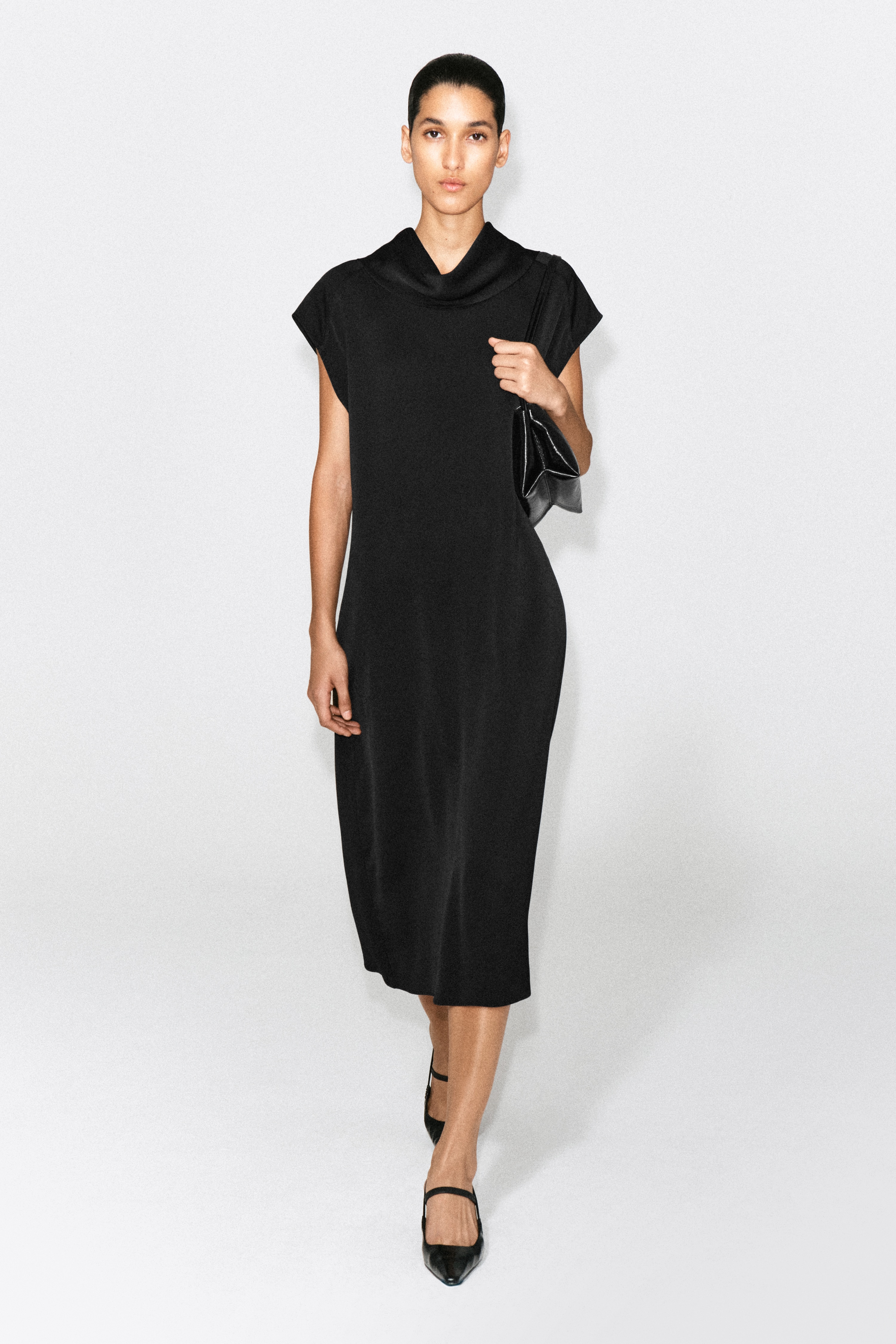 La robe midi en crÃªpe noire Ã  col bÃ©nitier est prÃ©sentÃ©e de face, avec un col bÃ©nitier drapÃ©, de courtes manches Ã  godets et une silhouette droite et dÃ©contractÃ©e. Une fermeture zippÃ©e est partiellement visible Ã  lâintÃ©rieur de lâencolure dos.