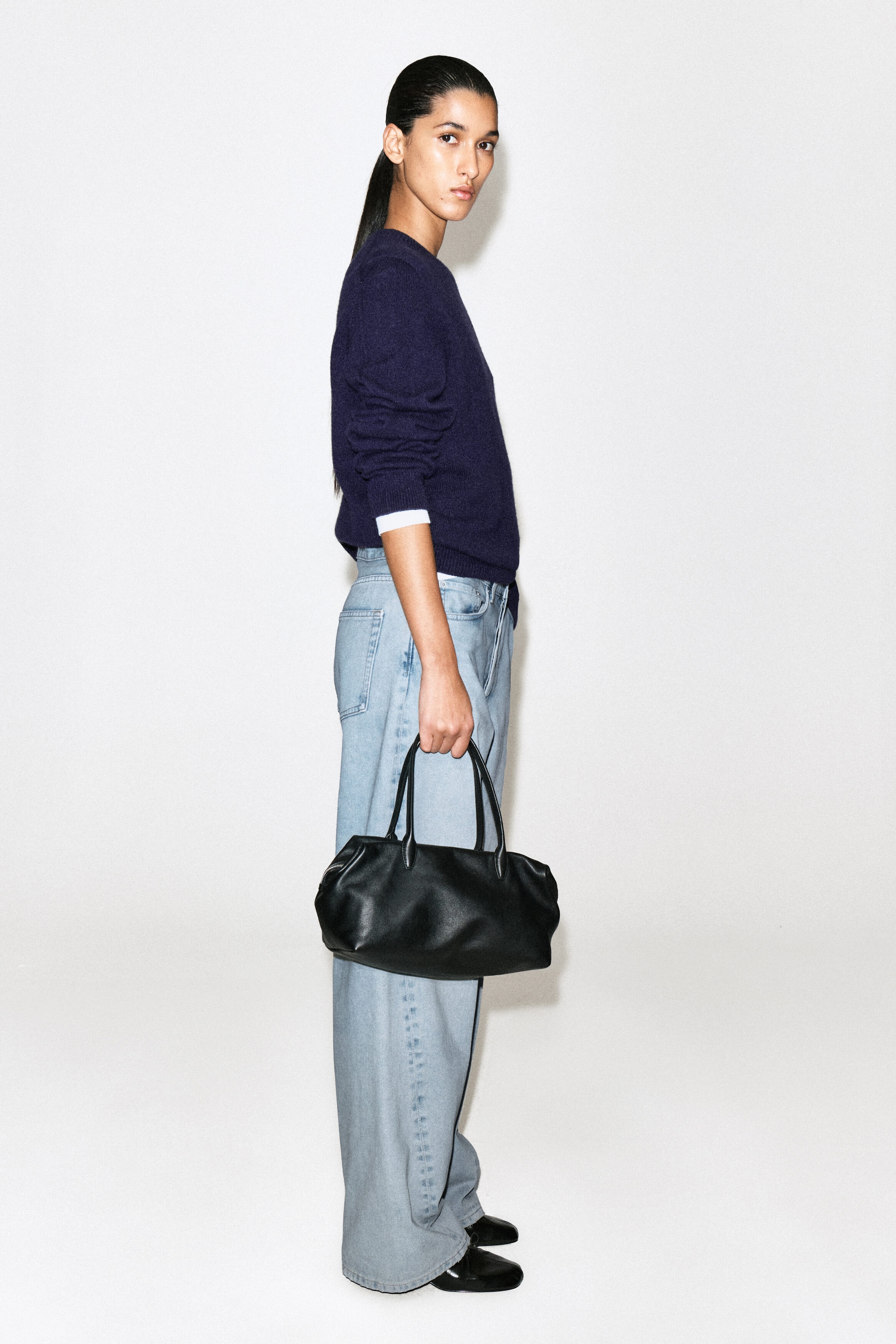 The Facade straight-leg jeans are shown in a light blue wash, facing right to highlight their relaxed, straight-leg silhouette. The jeans feature a high-waisted fit and a full-length cut, pooling slightly over black shoes.