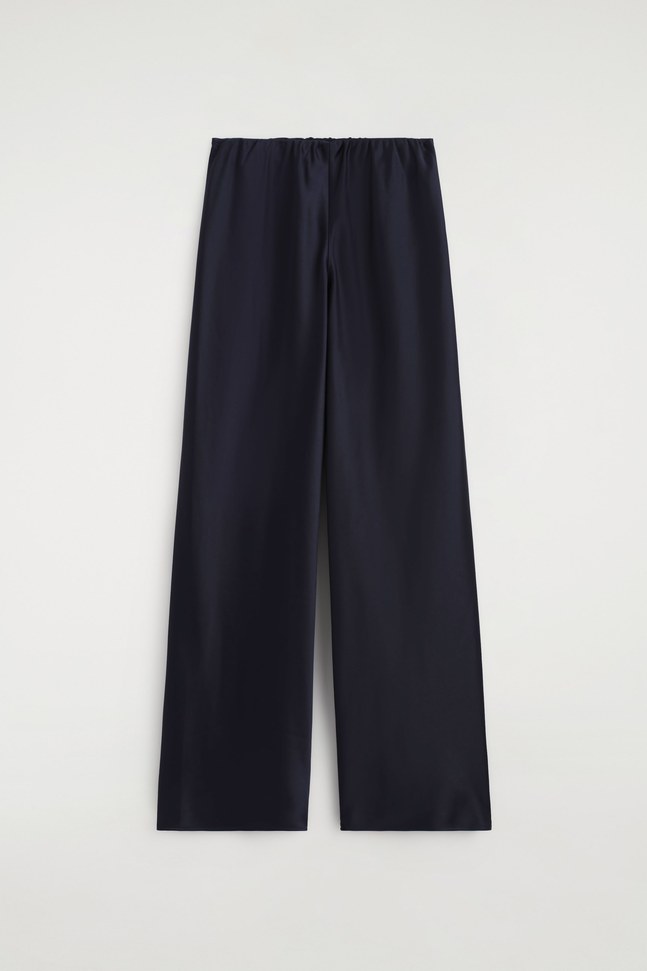 Agrandir l'image: Pantalon large bleu foncé présenté de face, avec un tissu à effet satiné et une taille élastiquée et froncée.