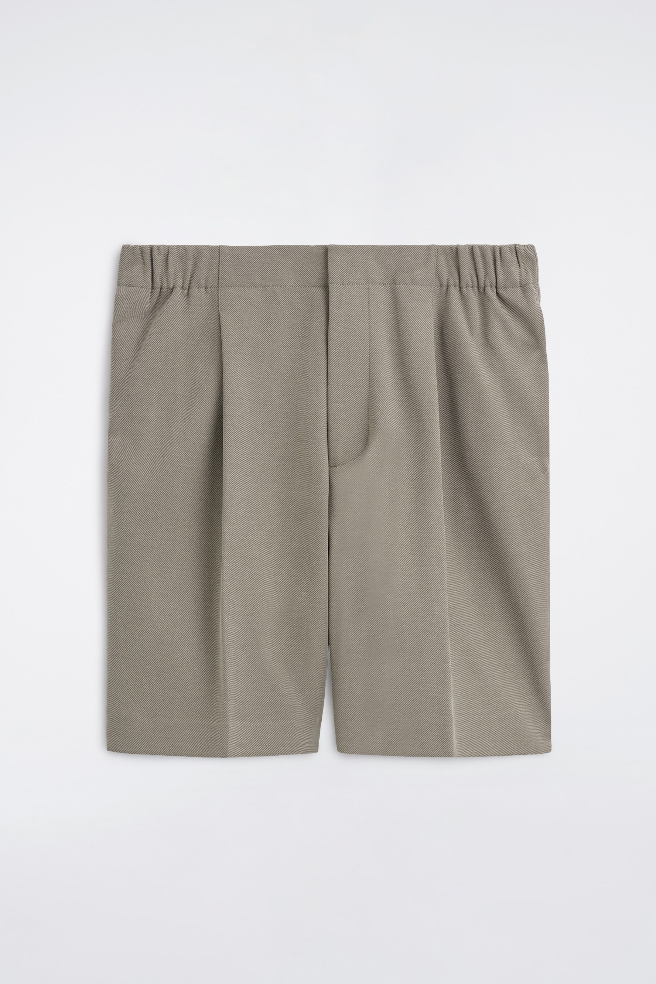 Grotere afbeelding bekijken: De Tailored Bonded-Twill Shorts worden getoond in een vooraanzicht, waarbij een gestructureerde taupegrijze stof te zien is met een platte tailleband aan de voorkant en elastische zijpanelen. De shorts hebben enkele plooien die overgaan in scherpe middenvouwen langs de pijpen, samen met zijzakken en een verborgen voorsluiting.