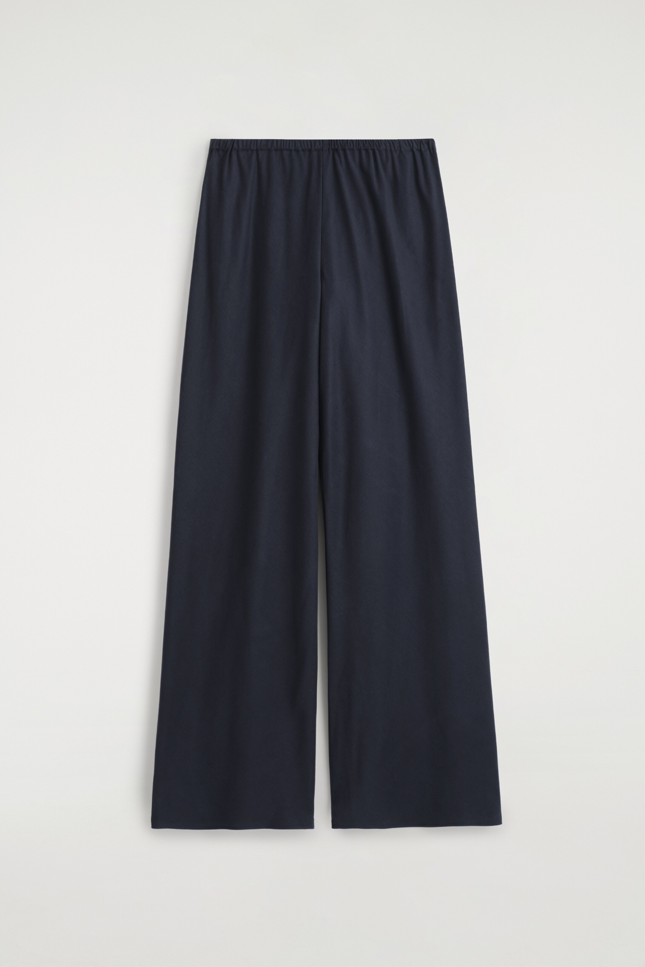 Größeres Bild anzeigen: Eine dunkelblaue Hose mit weitem Bein wird von vorne präsentiert, mit einem elastischen Bund und einem fließenden Fall.