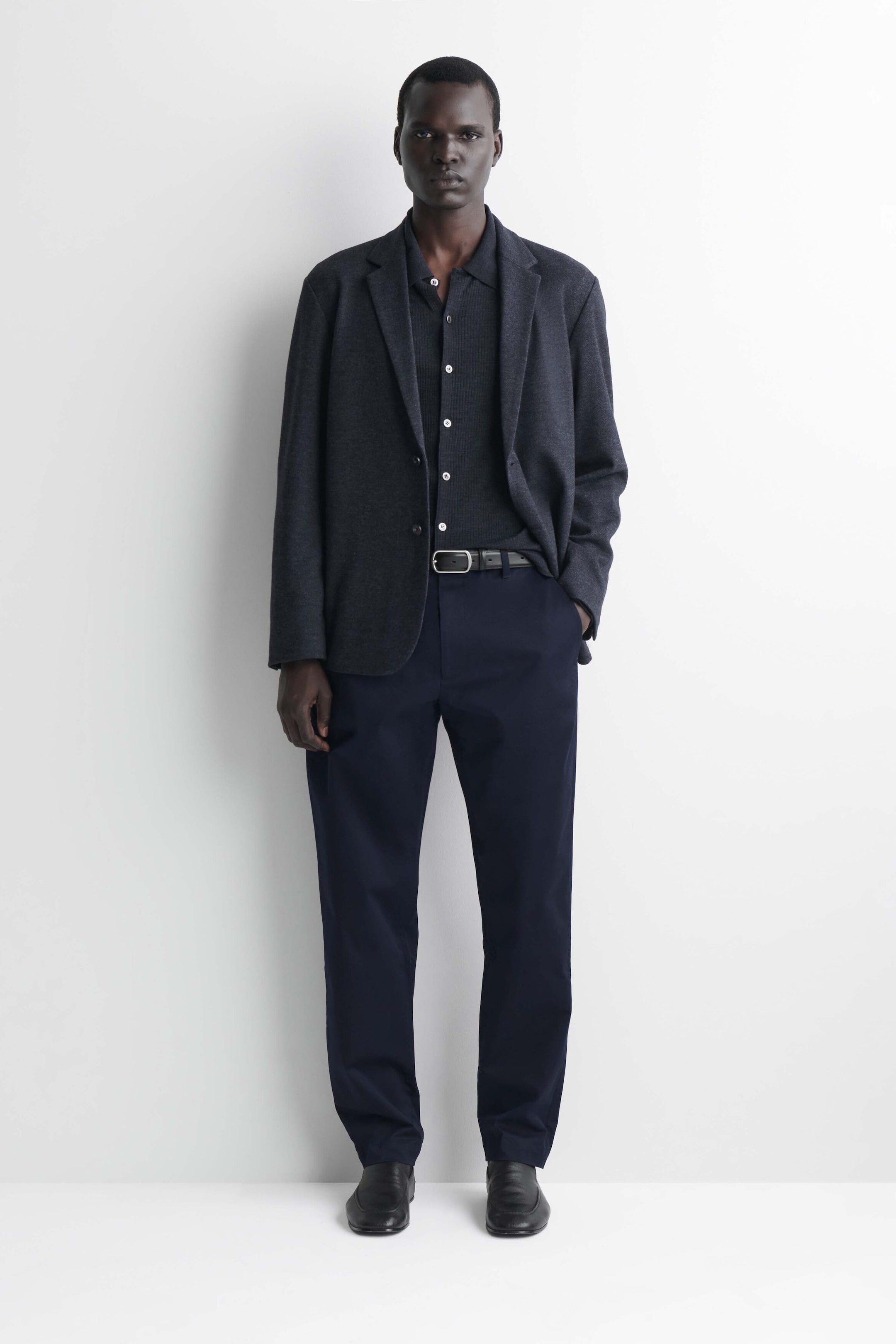 I chinos slim-fit dritti in cotone blu navy sono mostrati frontalmente, abbinati a una cintura in pelle nera in vita. I pantaloni cadono in una silhouette dritta, pulita e strutturata, posando ordinatamente su scarpe in pelle nera. I chinos slim-fit dritti in cotone blu navy sono mostrati frontalmente, abbinati a una cintura in pelle nera in vita. I pantaloni cadono in una silhouette dritta, pulita e strutturata, posando ordinatamente su scarpe in pelle nera.