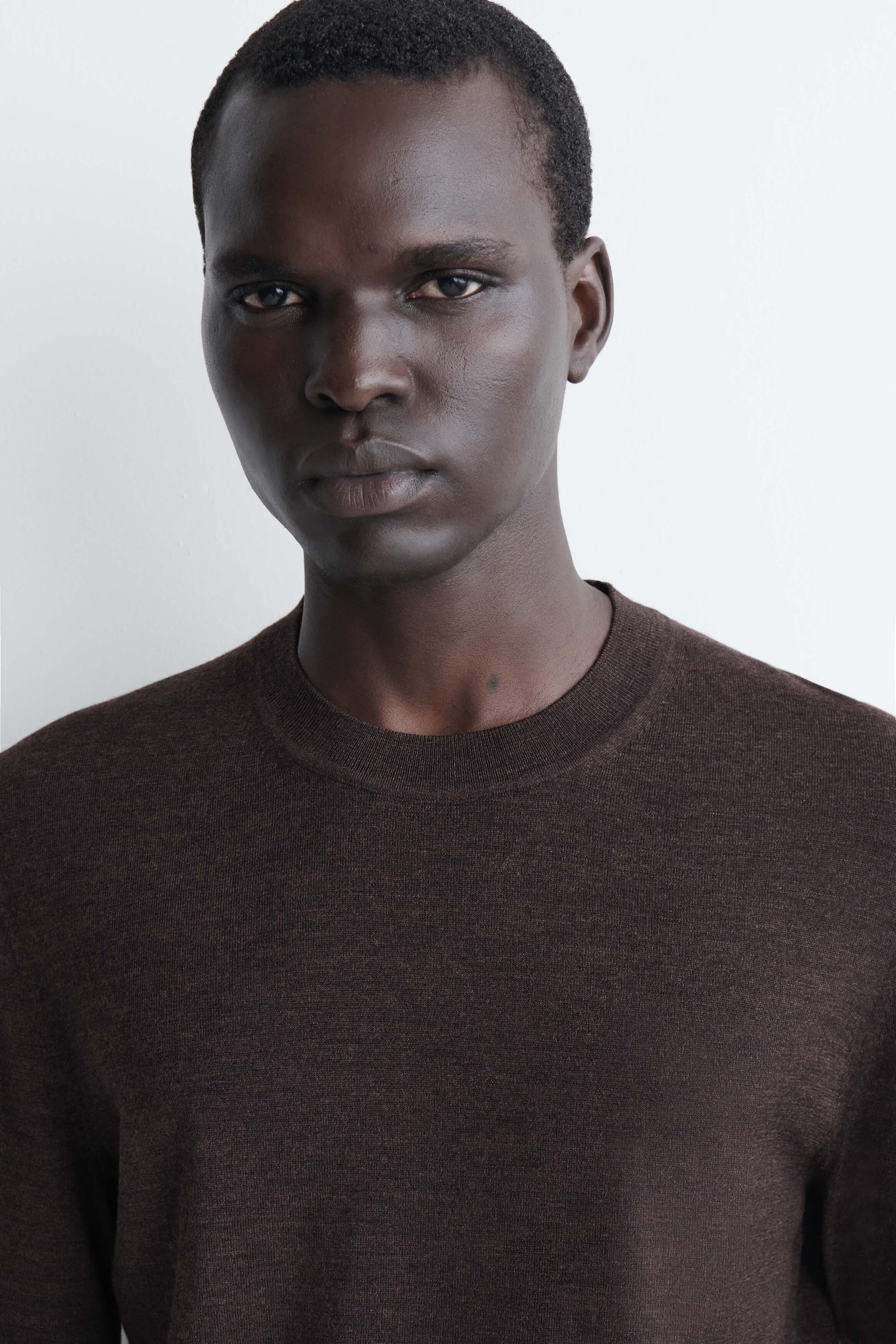 The slim merino wool crew-neck sweater in dark brown is shown in a close-up, front-facing view. It features a fine-knit texture and a classic ribbed crew-neck collar. The slim merino wool crew-neck sweater in dark brown is shown in a close-up, front-facing view. It features a fine-knit texture and a classic ribbed crew-neck collar.