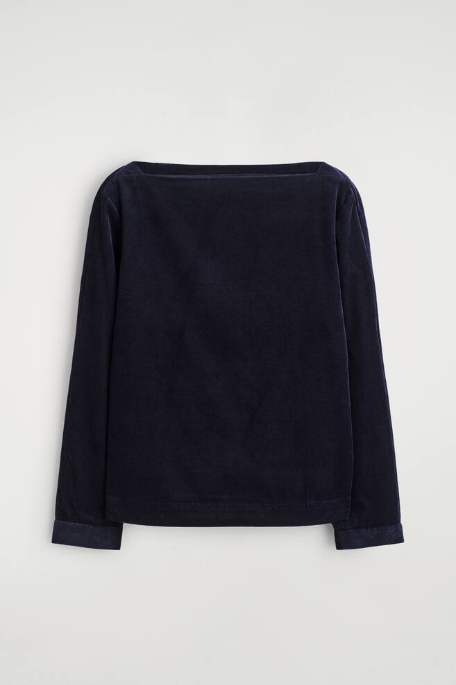 Een donkerblauwe corduroy top wordt van de VOORKANT gepresenteerd, met een kenmerkende corduroy textuur en zichtbare verticale ribbels overal. Het heeft een rechte, brede halslijn en lange mouwen met eenvoudig gezoomde manchetten. - 1