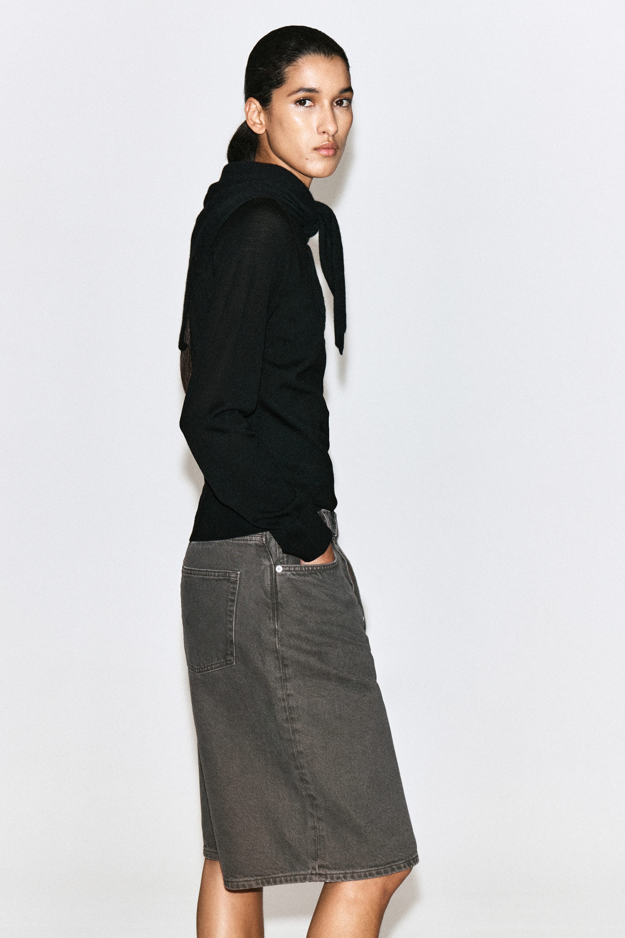 These longline denim shorts in a washed espresso hue are worn facing right, showcasing a high-rise waist, classic five-pocket design, and straight-leg silhouette that falls just above the knee. The shorts are paired with a black long-sleeve top. These longline denim shorts in a washed espresso hue are worn facing right, showcasing a high-rise waist, classic five-pocket design, and straight-leg silhouette that falls just above the knee. The shorts are paired with a black long-sleeve top.