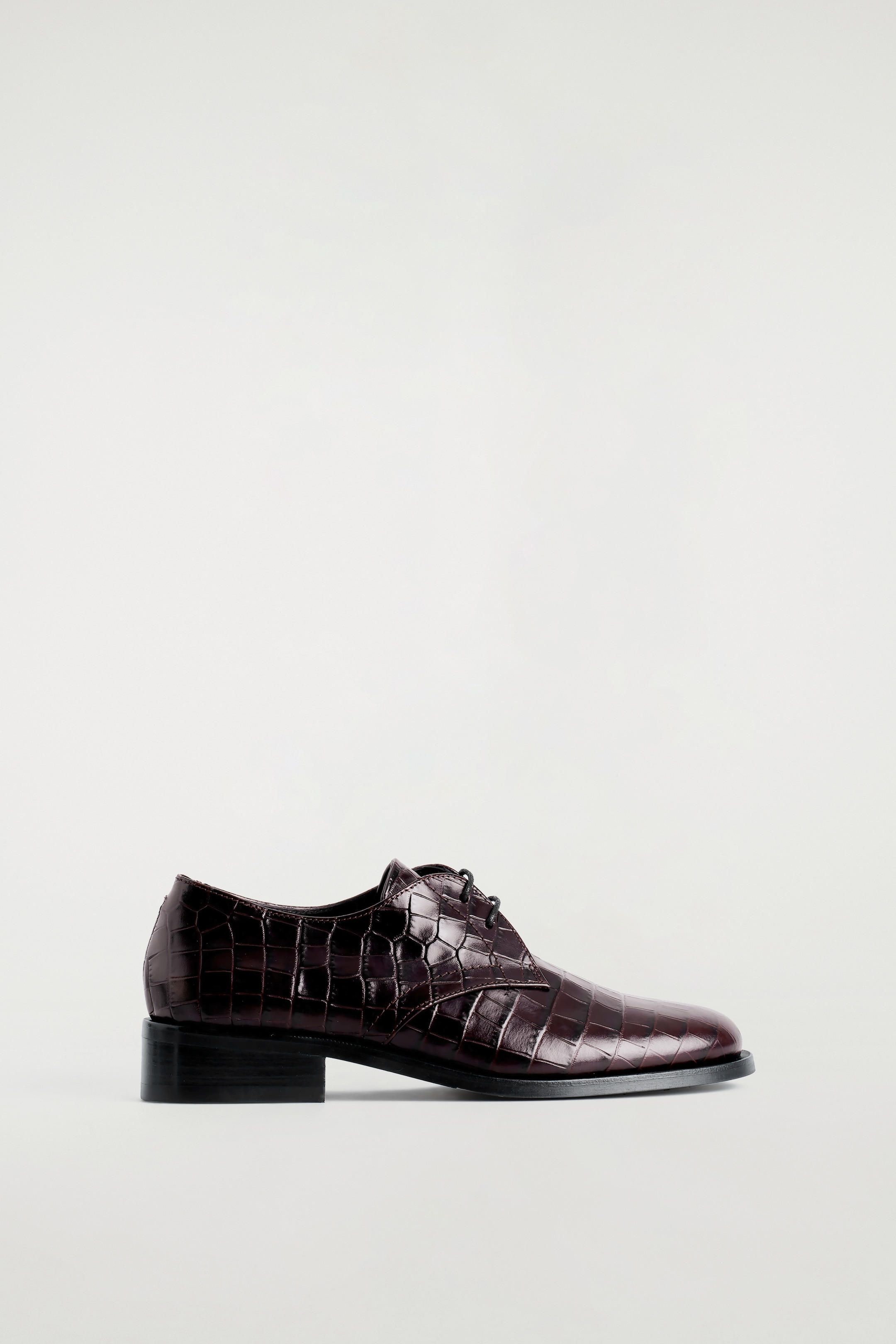 Grösseres Bild ansehen: Der rechte Derby-Schuh ist aus dunkel espressofarbenem Krokodilprägungsleder gefertigt und verfügt über eine abgerundete Zehenpartie und gewachste Baumwollschnürsenkel. Er ist auch mit einem niedrigen schwarzen Blockabsatz gestaltet.
