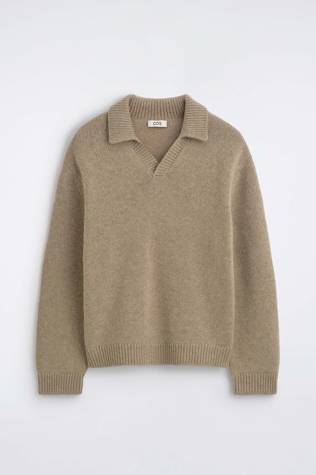 The chunky cashmere polo sweater is shown from the front, highlighting a textured beige knit with a spread collar and an open, buttonless V-neckline. It features long sleeves with ribbed cuffs and a matching ribbed hem.