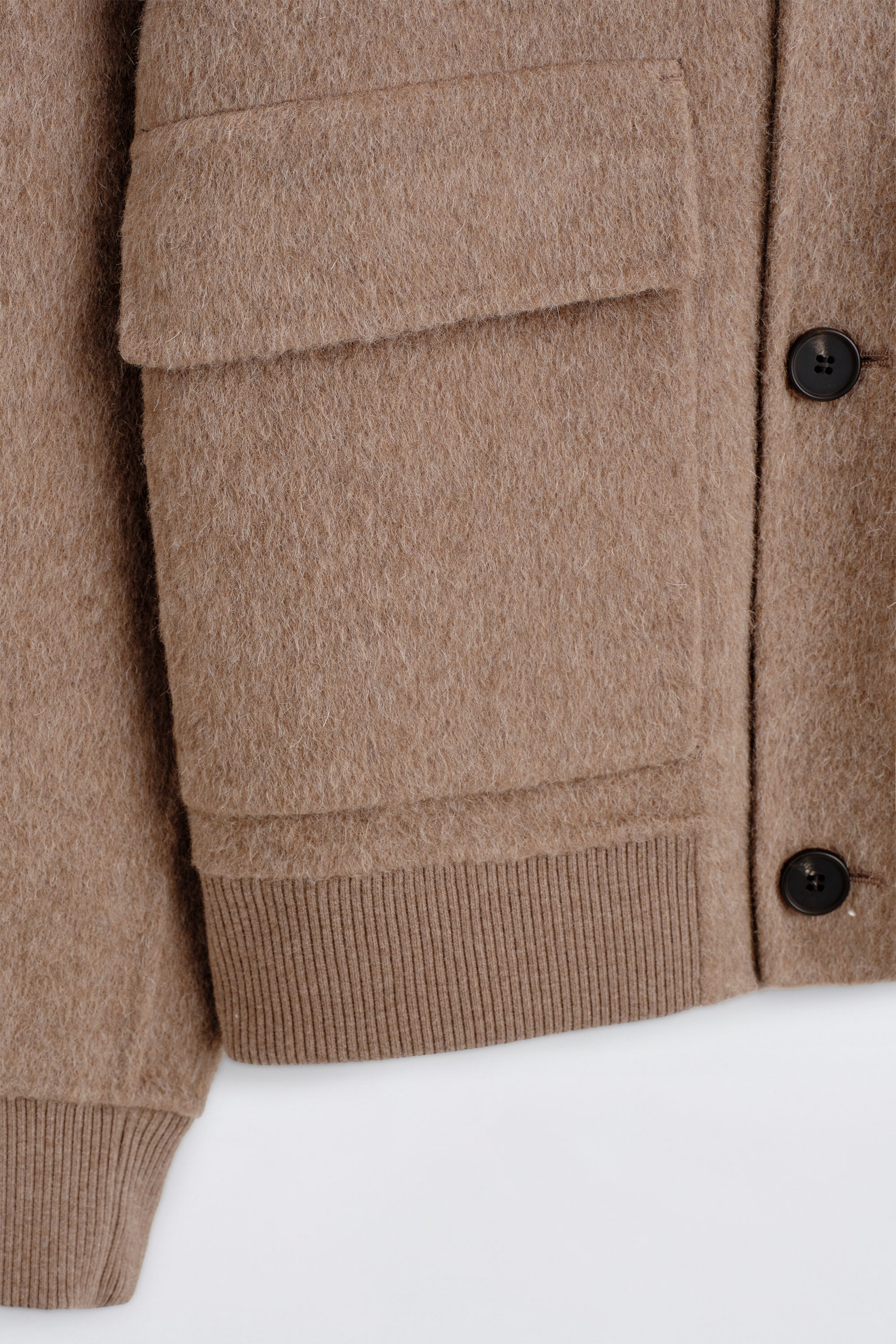 The double-faced blouson jacket is shown in a close-up front view, highlighting its textured brushed fabric in a warm camel color. It features a large front flap pocket, dark brown button closures, and matching ribbed knit trims at the hem and cuffs. The double-faced blouson jacket is shown in a close-up front view, highlighting its textured brushed fabric in a warm camel color. It features a large front flap pocket, dark brown button closures, and matching ribbed knit trims at the hem and cuffs.