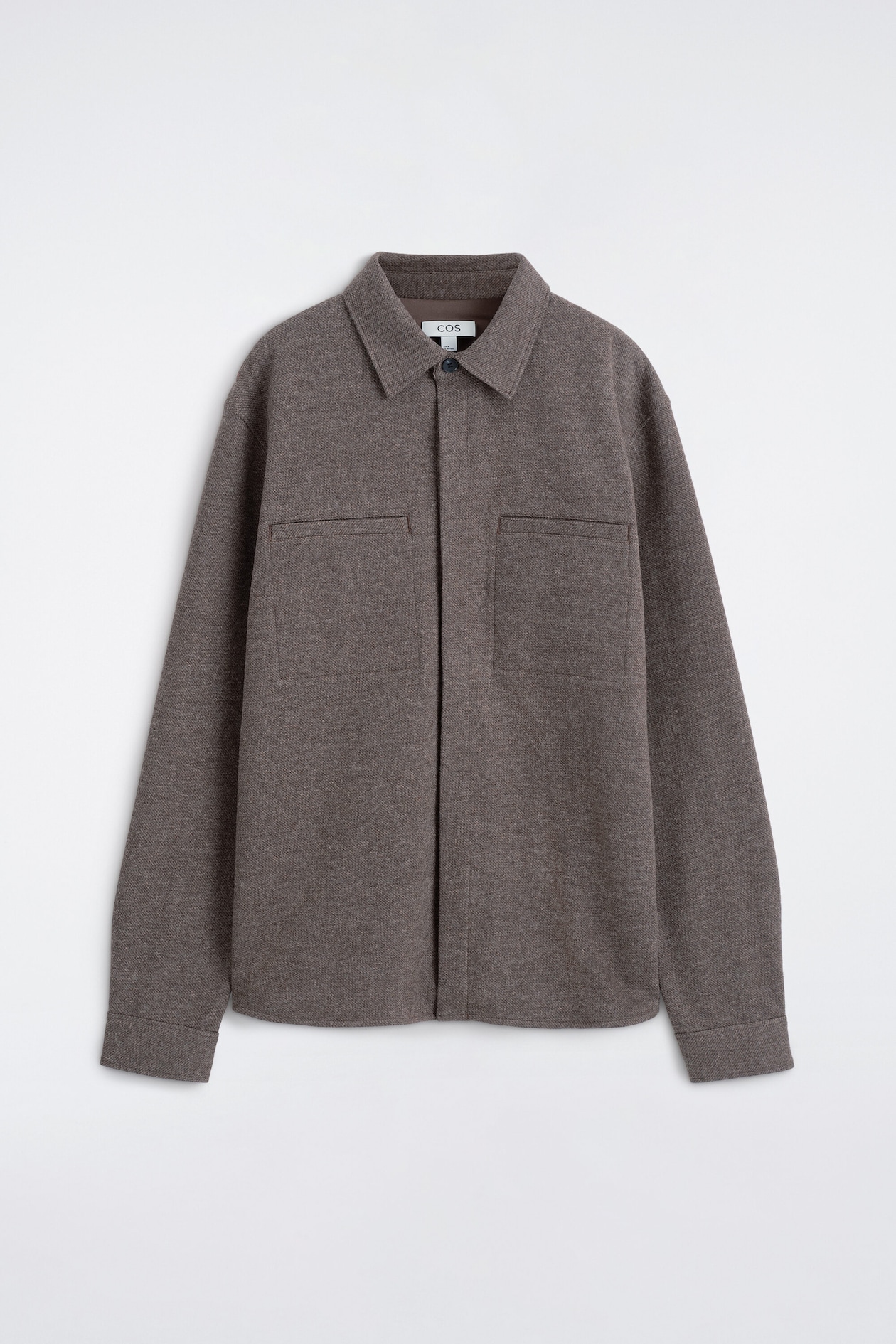 A brown shacket is shown from the front, featuring a classic collar and a button-down front closure. It features two large chest patch pockets with flaps, and its long sleeves end in simple cuffs.