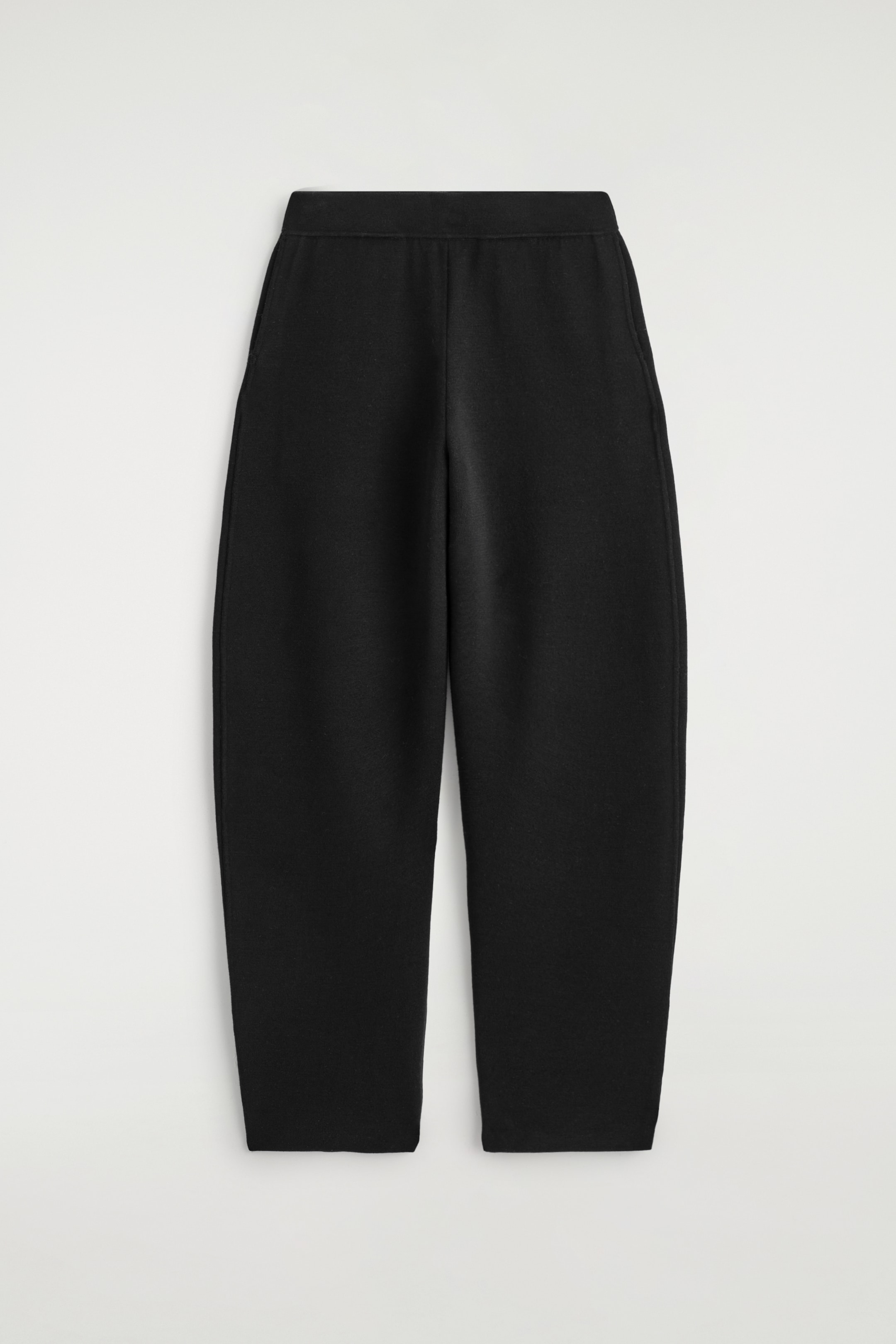 Visualizza immagine più grande: I pantaloni neri a maglia sono mostrati dal davanti, presentano una silhouette scultorea a gamba a barile, una texture liscia e densa, tasche laterali verticali sottili e una cintura piatta.